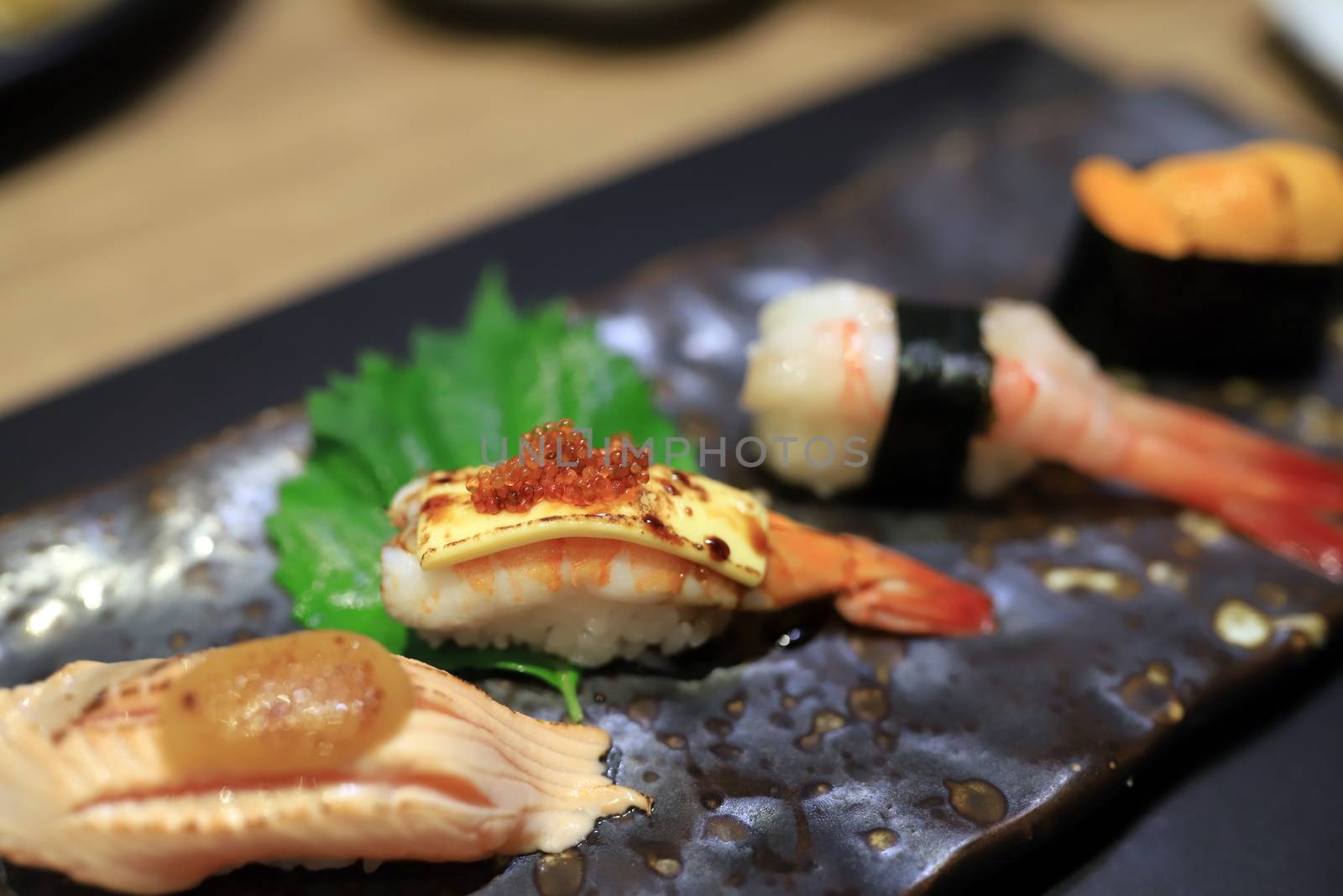 Shrimp sushi topped with grilled cheese and topped with orange roe On a traditional Japanese plate in a Japanese restaurant. Selective focus. by joker3753