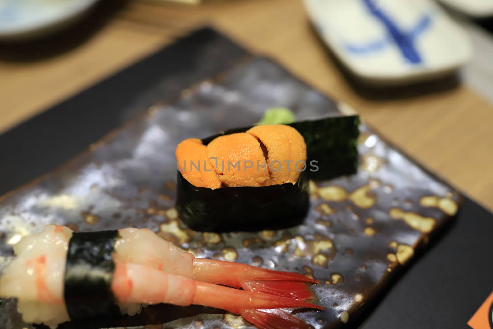 Sea urchin sushi wrapped in seaweed on a traditional Japanese dish in a Japanese restaurant. Selective focus. by joker3753