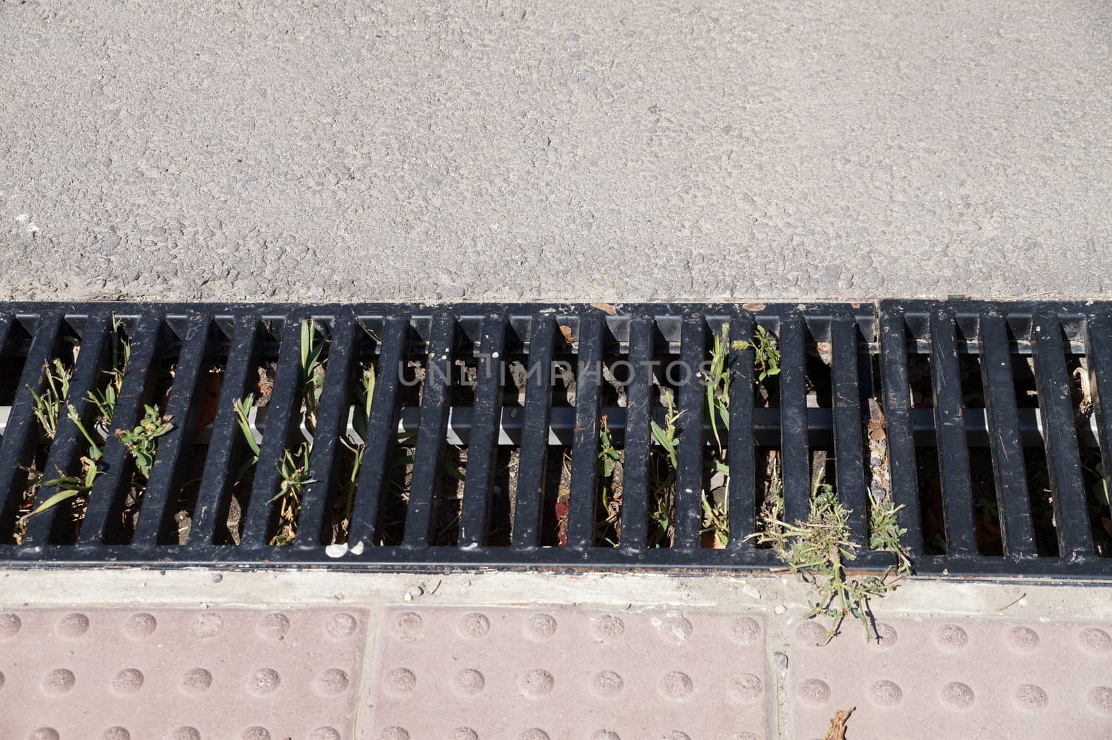 cast iron street drainage on the sidewalk close up by Annado