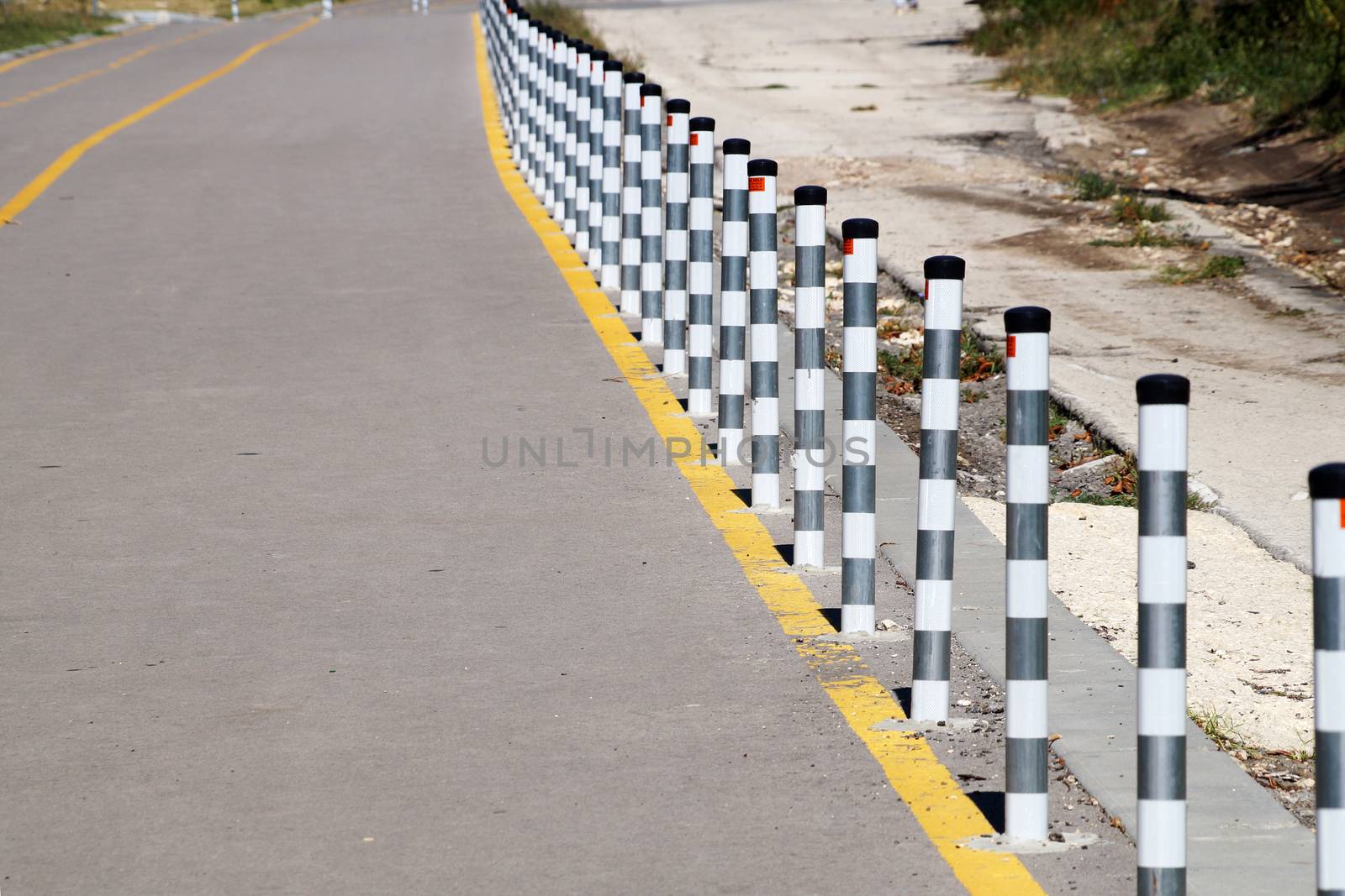 fence posts on the pedestrian sidewalk close up by Annado