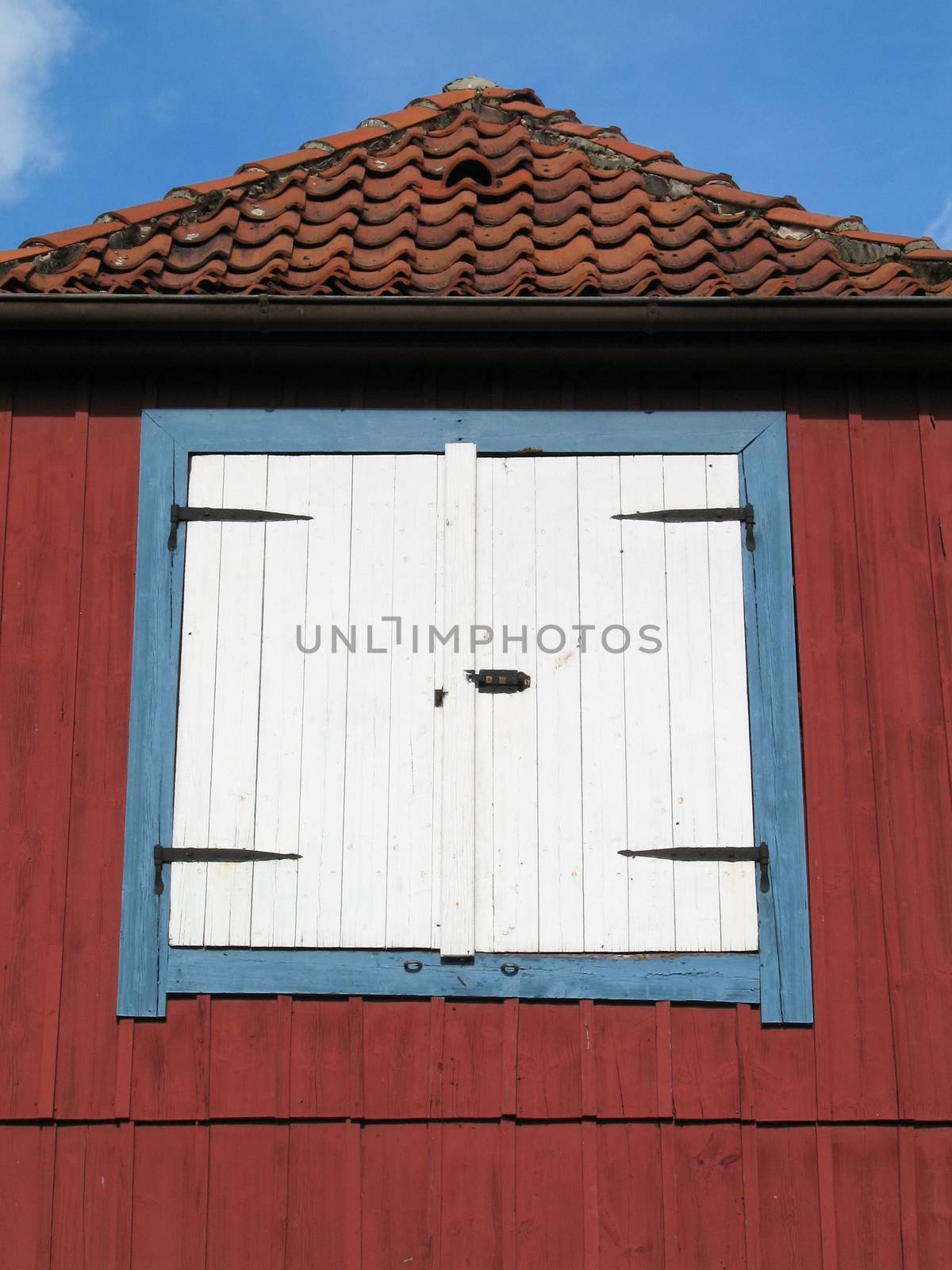 A white hatch is situated on the side of a red painted house.