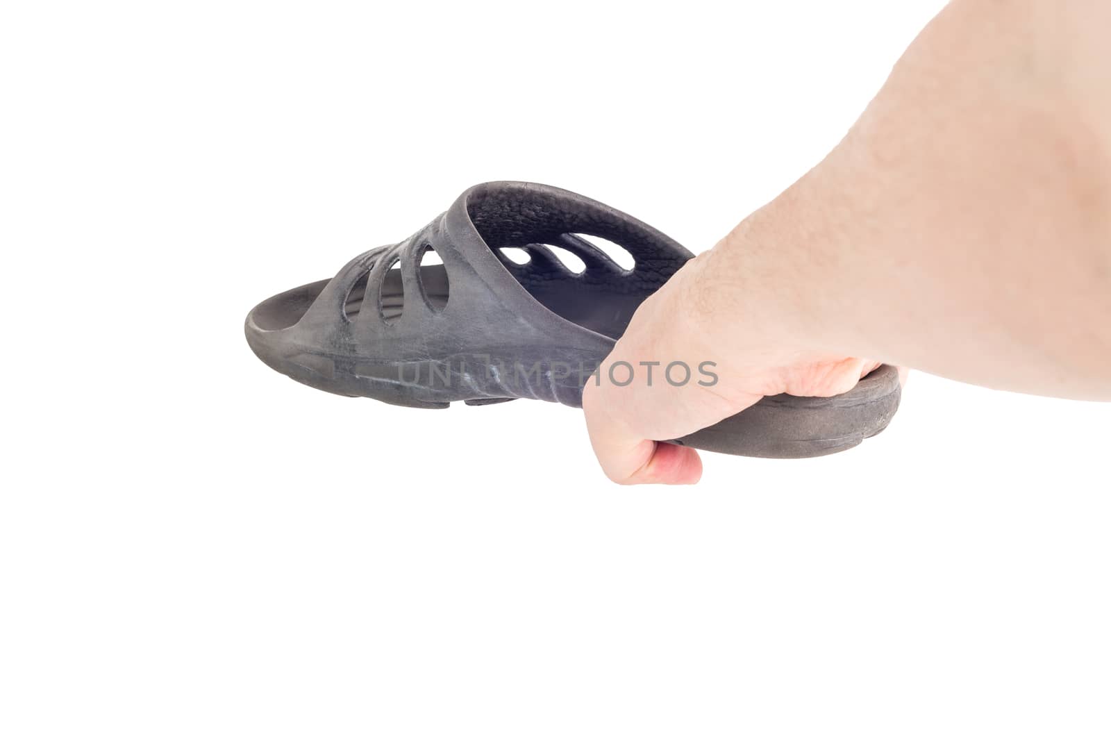 caucasian hand holding black rubber slipper like weapon against cockroach.
