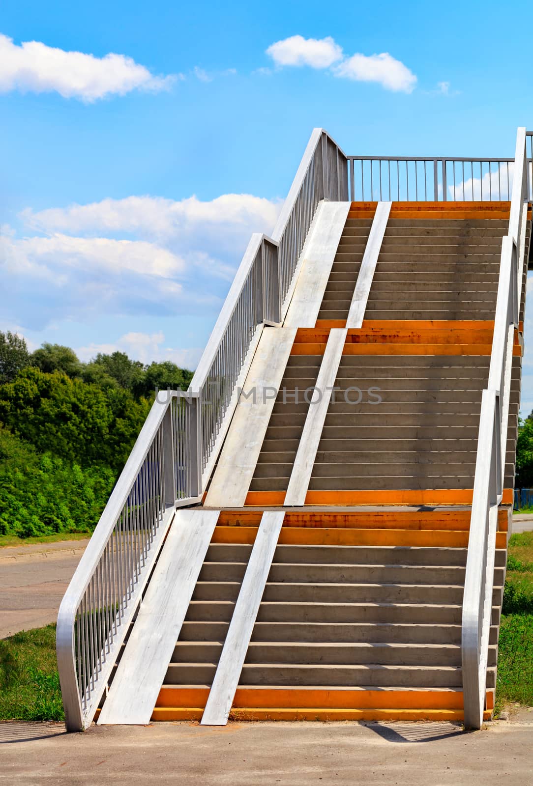 Crosswalk stairs lead up over highway with blue sky and white clouds, career concept, vertical image, copy space.