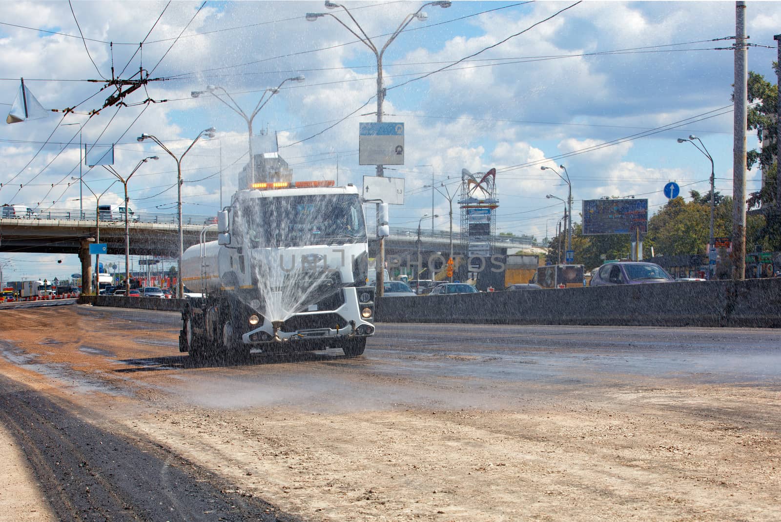 A watering machine waters the road on a hot sunny day. by Sergii