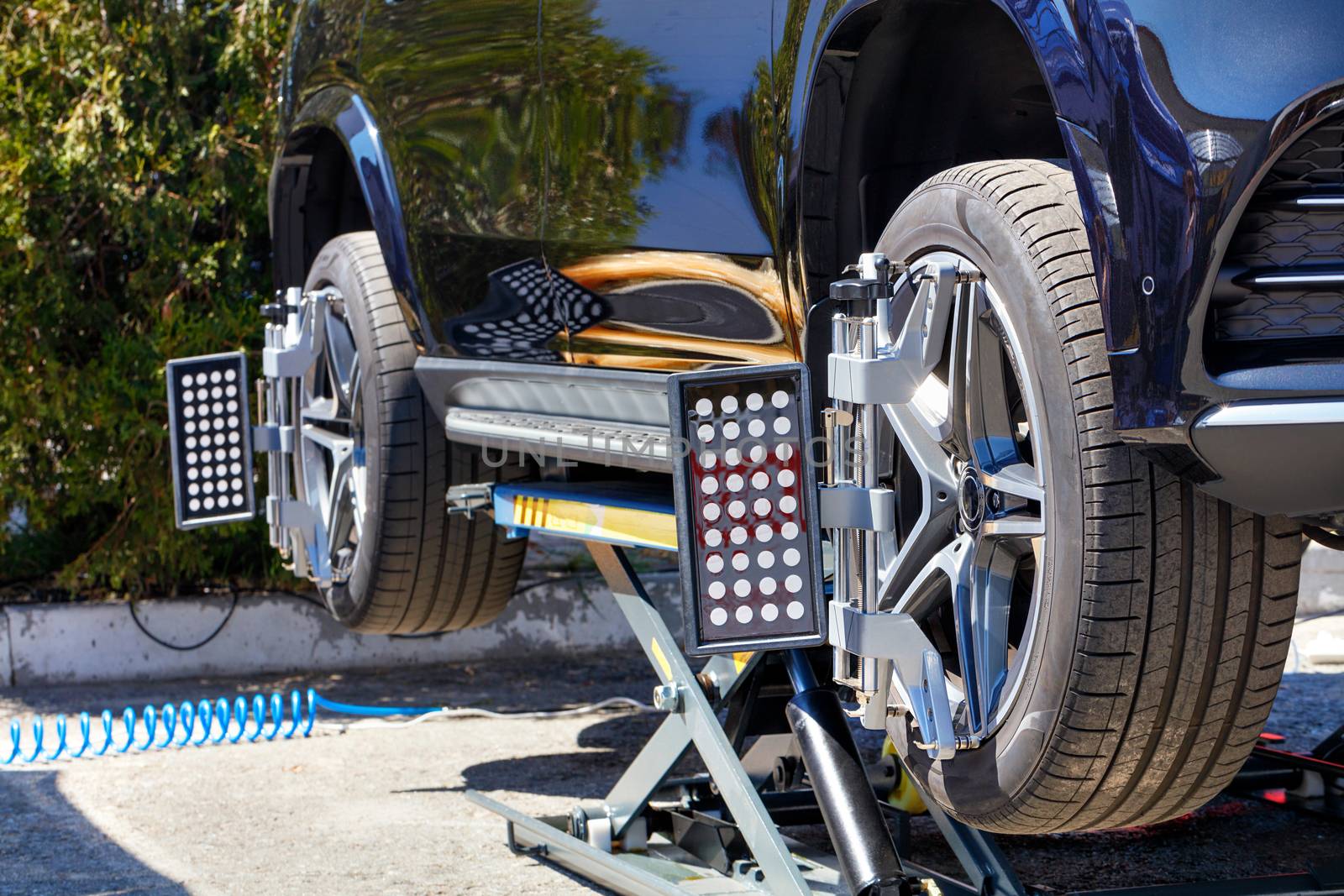 Equipment for aligning the wheels of a car on a mobile stand in a repair station. The car stands on a stand with wheel sensors for camber alignment.