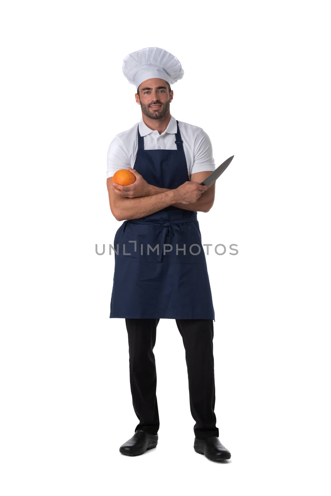 Male cook in apron and hat holding orange and knife isolated on white background, full length portrait