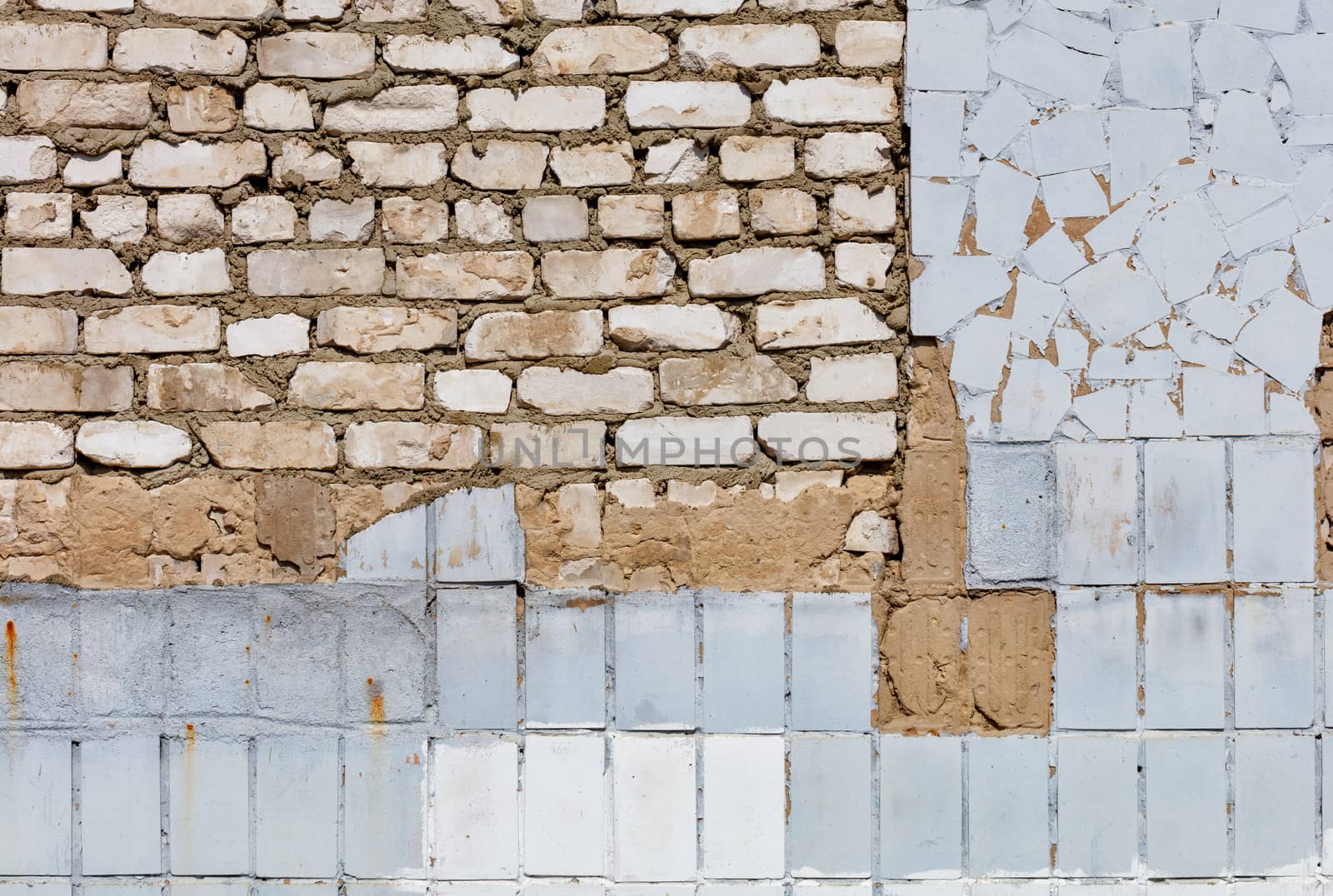 The texture of the old wall from peeling plaster and tiles, white bricks and cement mortar, close-up. by Sergii