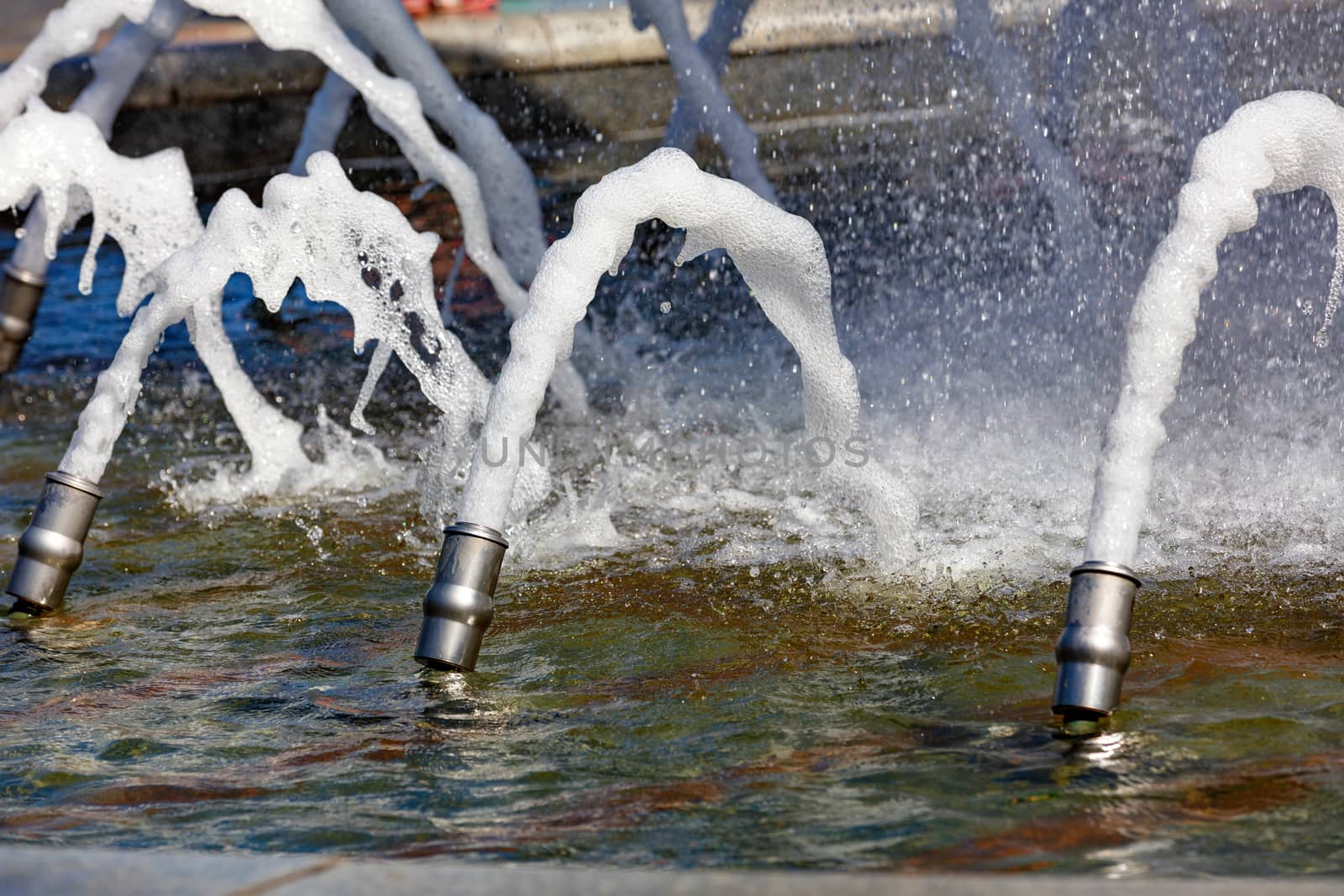 Thick foaming jets of water burst from metal cannons in the city's granite fountain. by Sergii