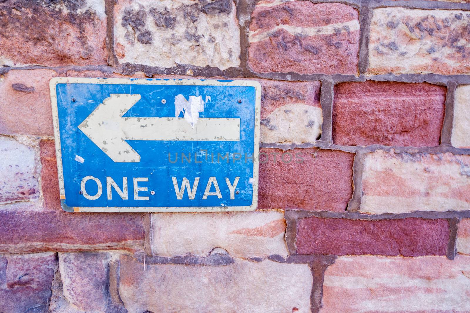 Brick Wall with Blue and White One Way Sign