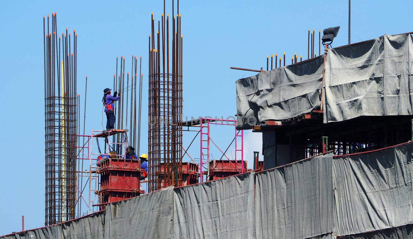 High construction site and labors working and around with concrete cement metal material.