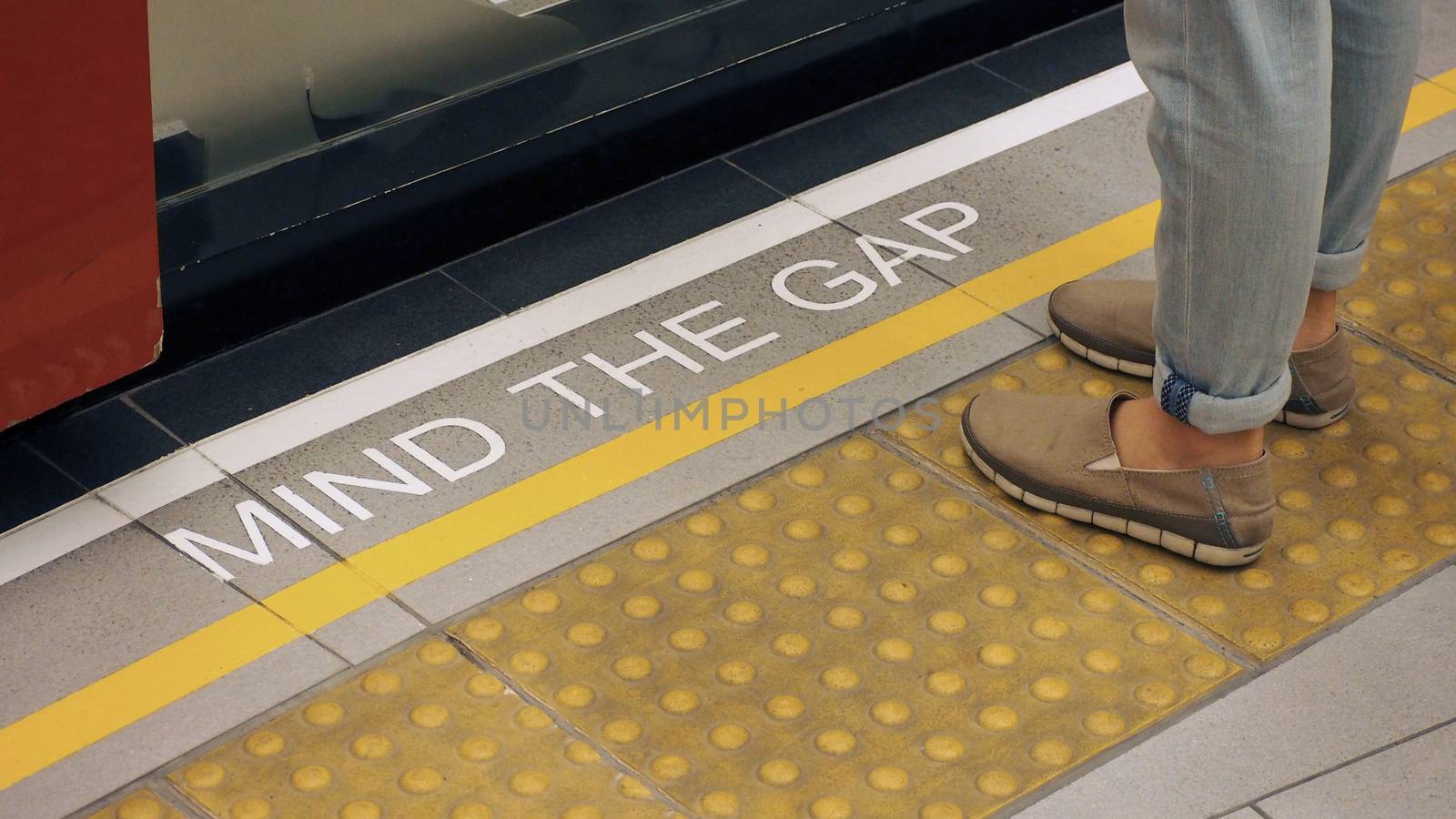 Text sign on floor between train and platform "Mind the gap" with white color and high angle view. 