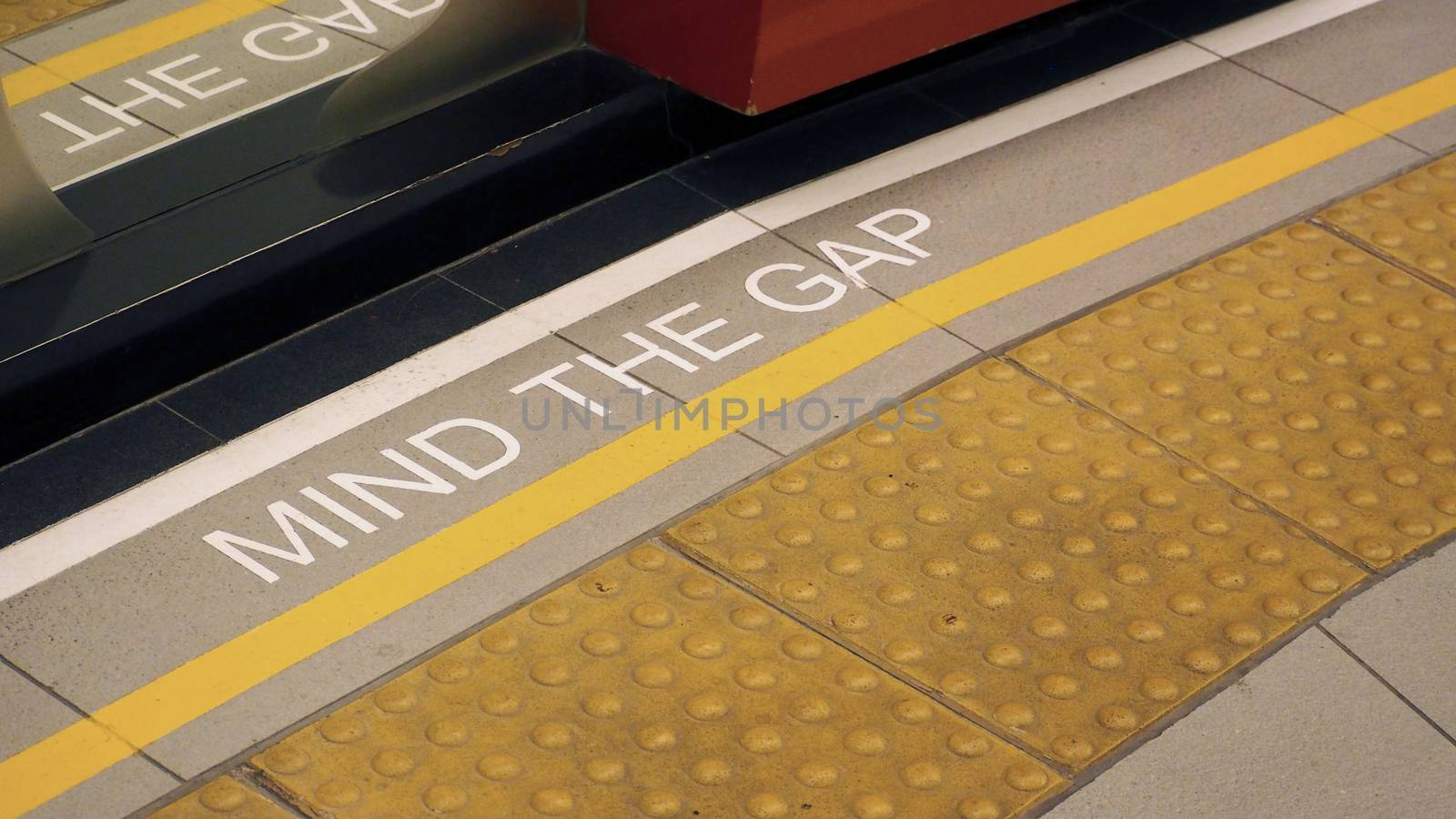 Text sign on floor between train and platform "Mind the gap" with white color and high angle view. 