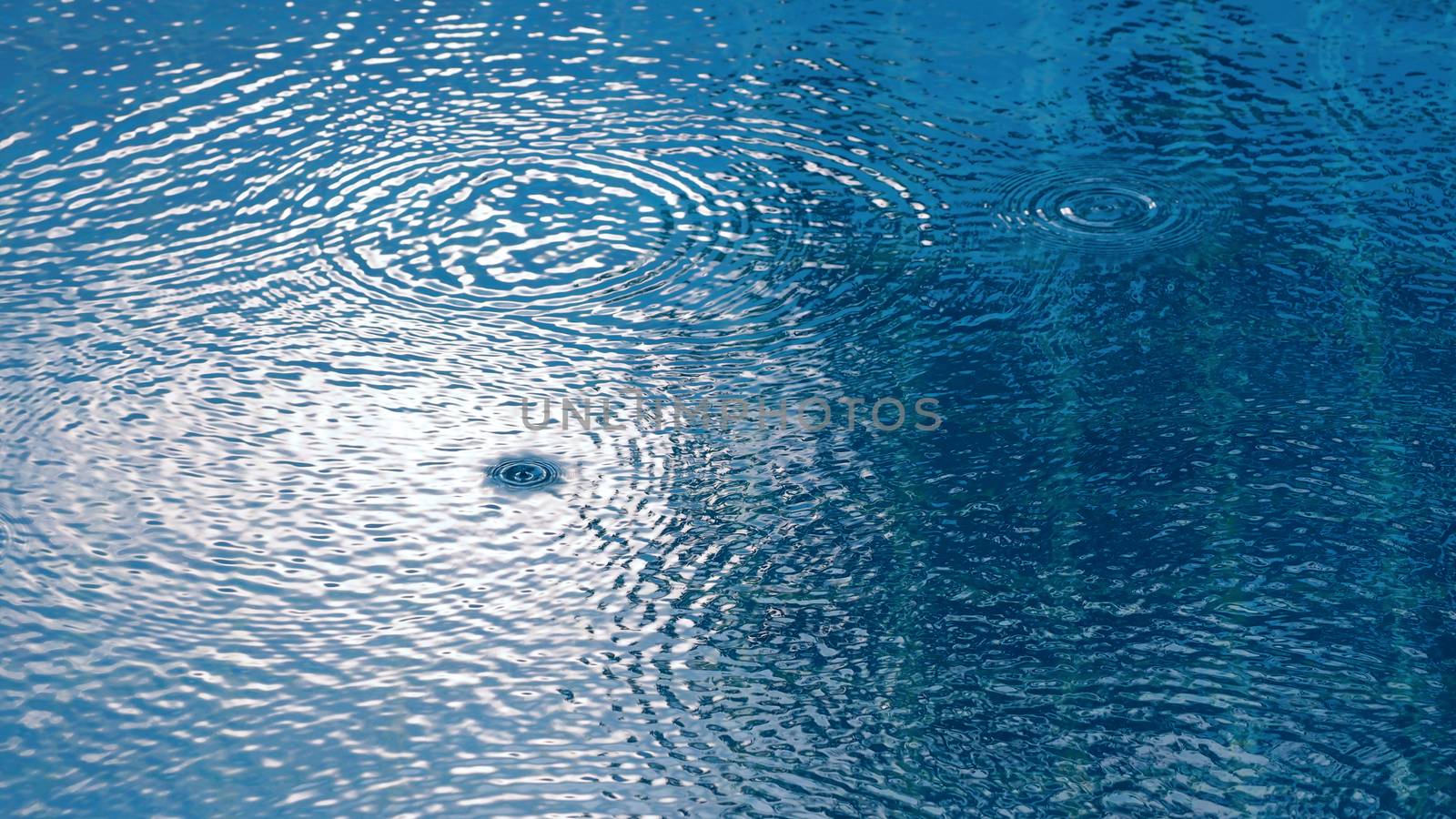 Rain drop on the water pool and have sunlight reflection on surfuce texture.