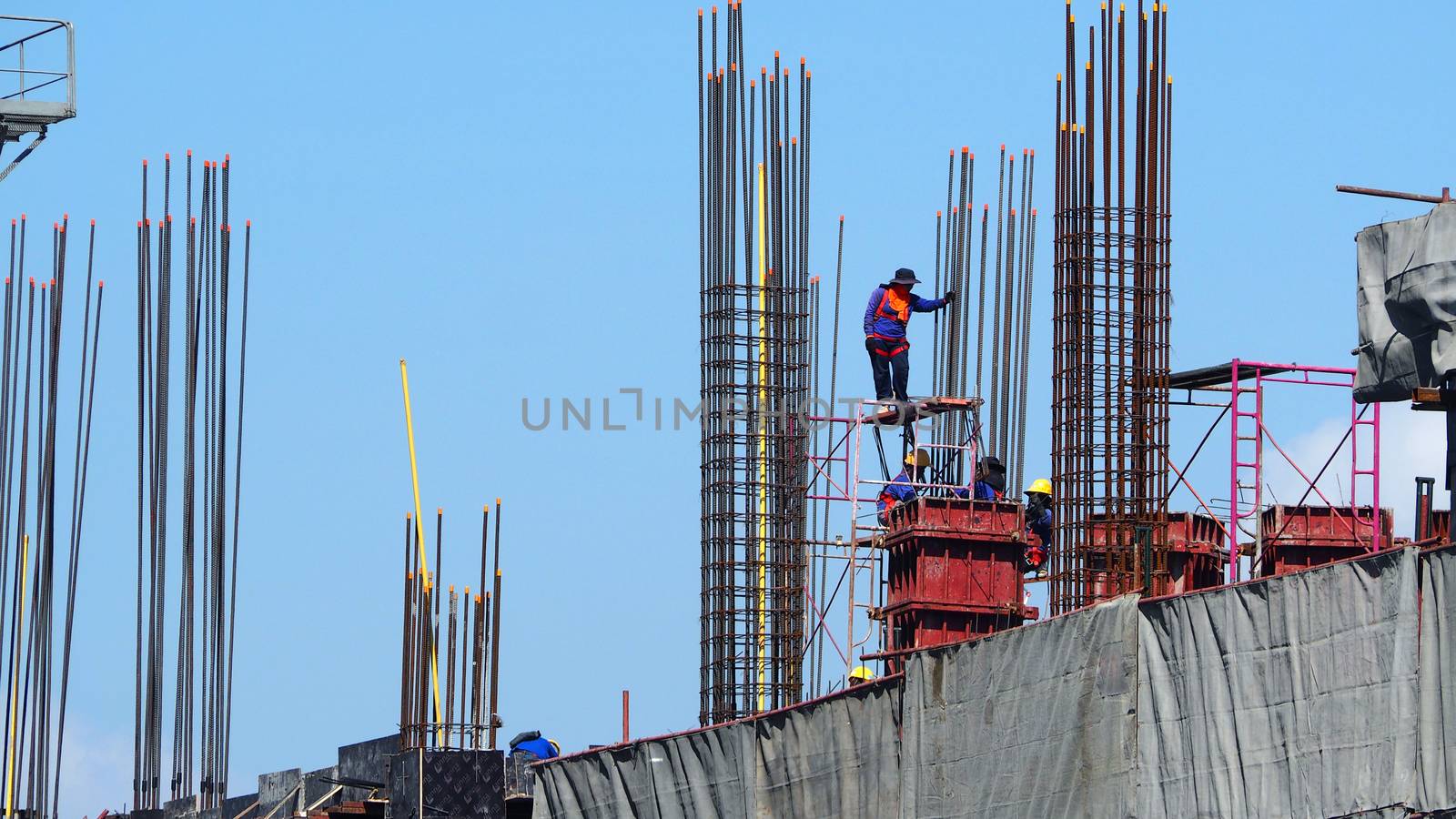 Construction site and worker that working on high building and concrete steel material.