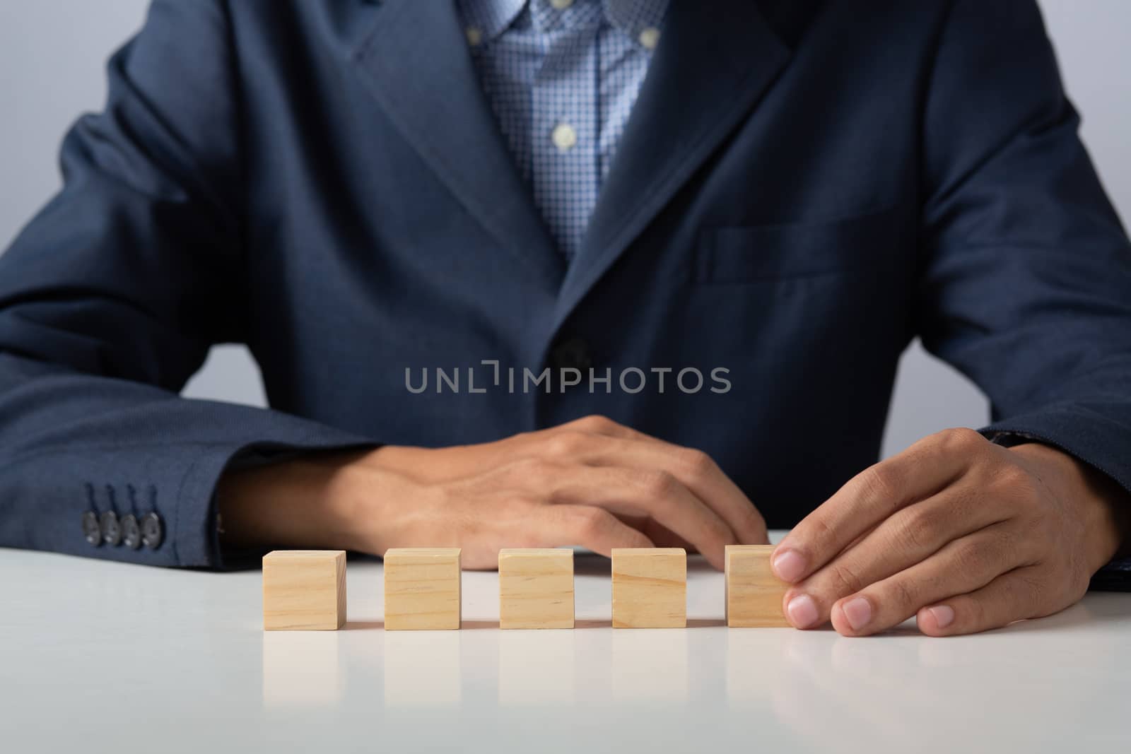 Hands of entrepreneur business man holding wooden blocks placing to a structure, Concept of teamwork, strategy, professional manager work for executive investor to corporate wealth of fundamental.