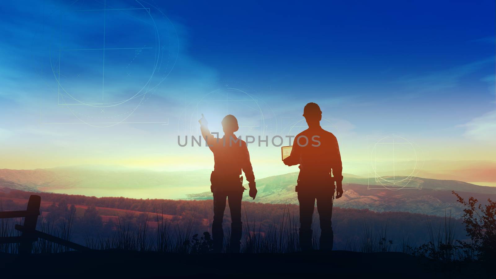 Two silhouettes of construction engineers looking from a hill at a future site of wind farm.