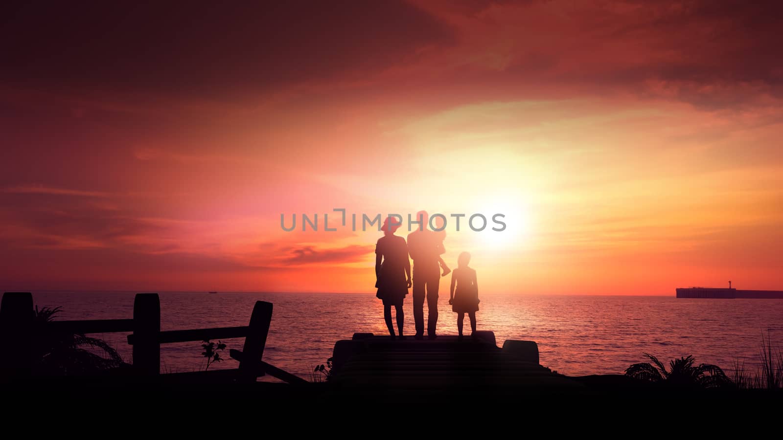 A family stands on the ocean against a bright red sunset.