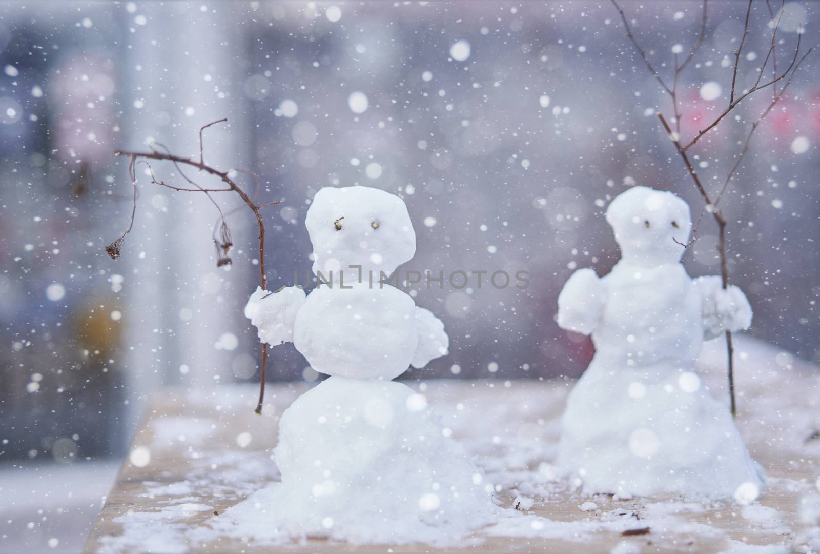 Two little cute snowmen with branches instead of hands Christmas background New Year mood.