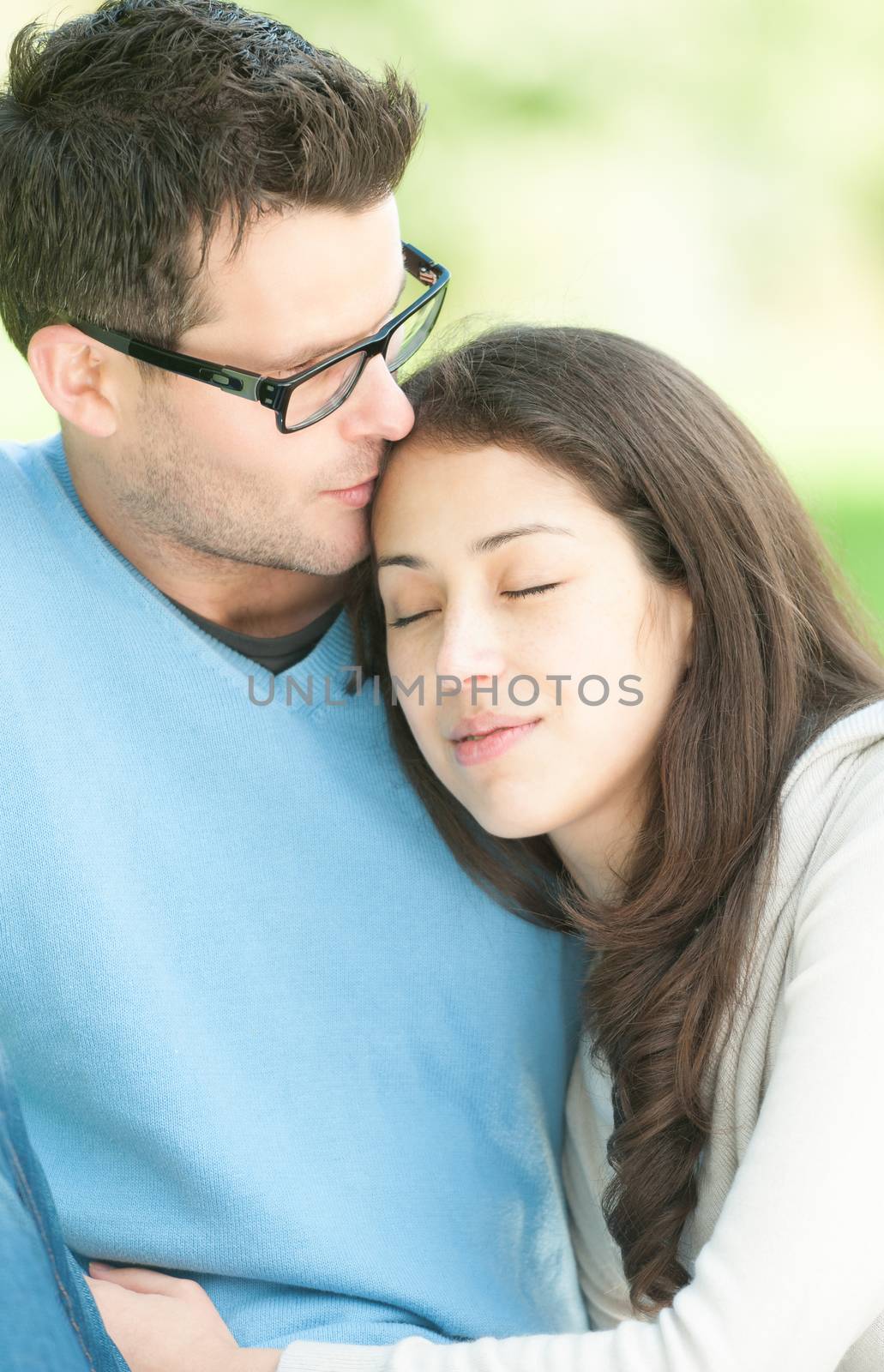 Portrait of young sweet couple spending time outdoor together. Woman leaning on man's shoulder with her eyes closed. Quiet and peaceful atmosphere. Romantic relationships. Family and love.