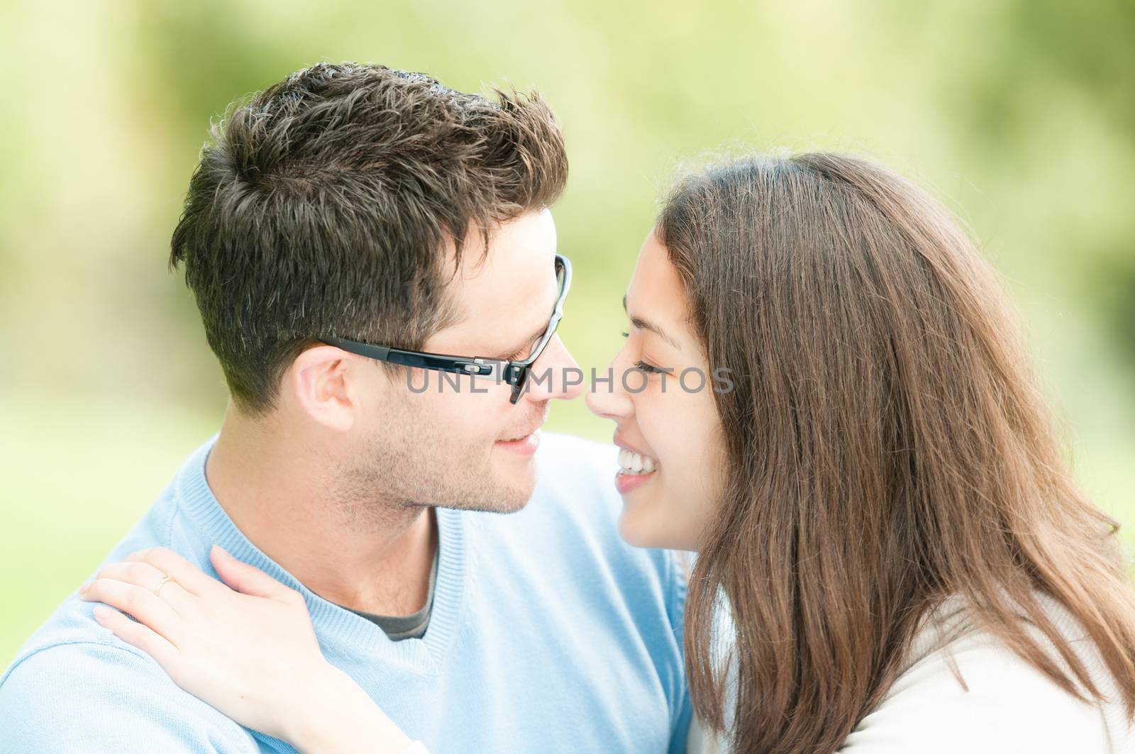 Pretty woman and man in glasses kissing in park. by Yolshin