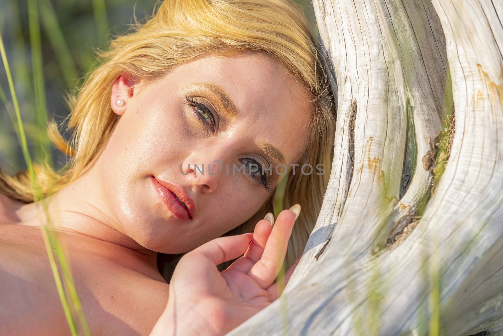 A gorgeous nude blonde model enjoys a summers day outdoors in a park