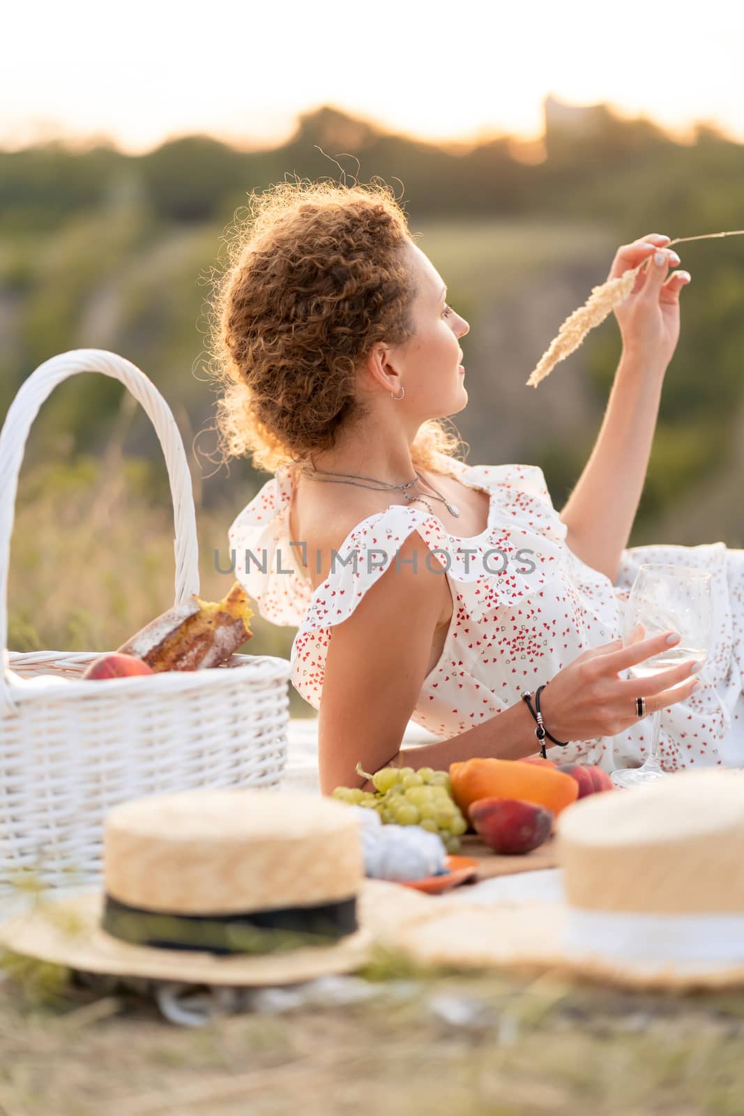 Beautiful girl enjoys a picnic at sunset in a beautiful place