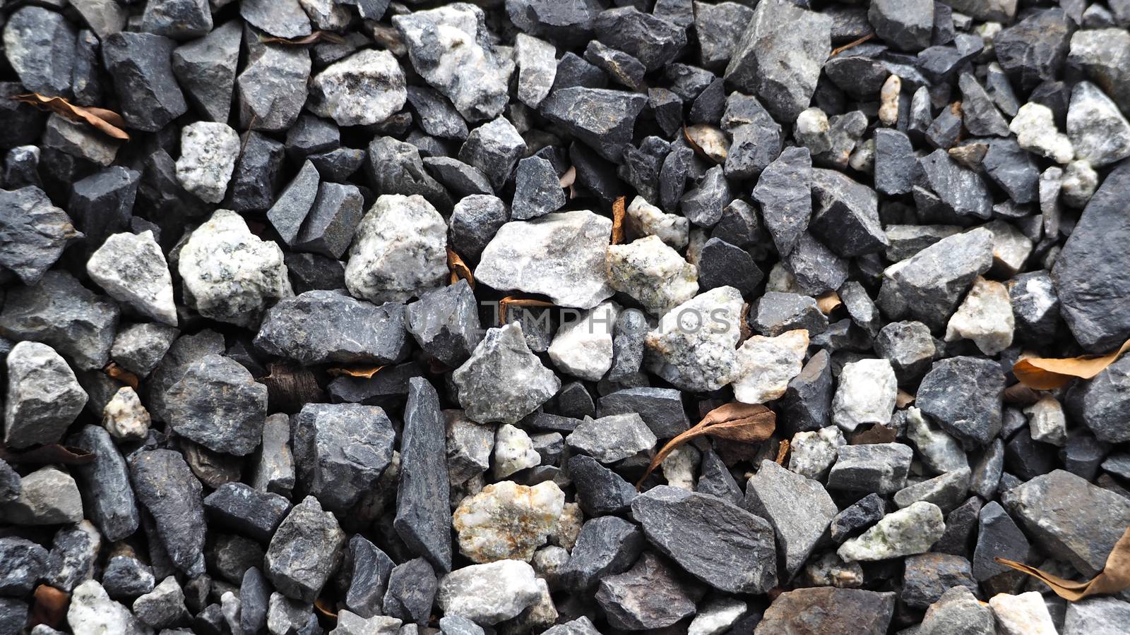 Grey color small stone floor texture which have small dry leaf between cobble and top view close-up.