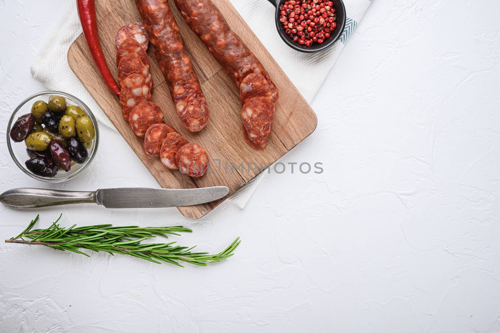 Traditional chorizo cuts with spices and ingredients on white textured background with space for text.
