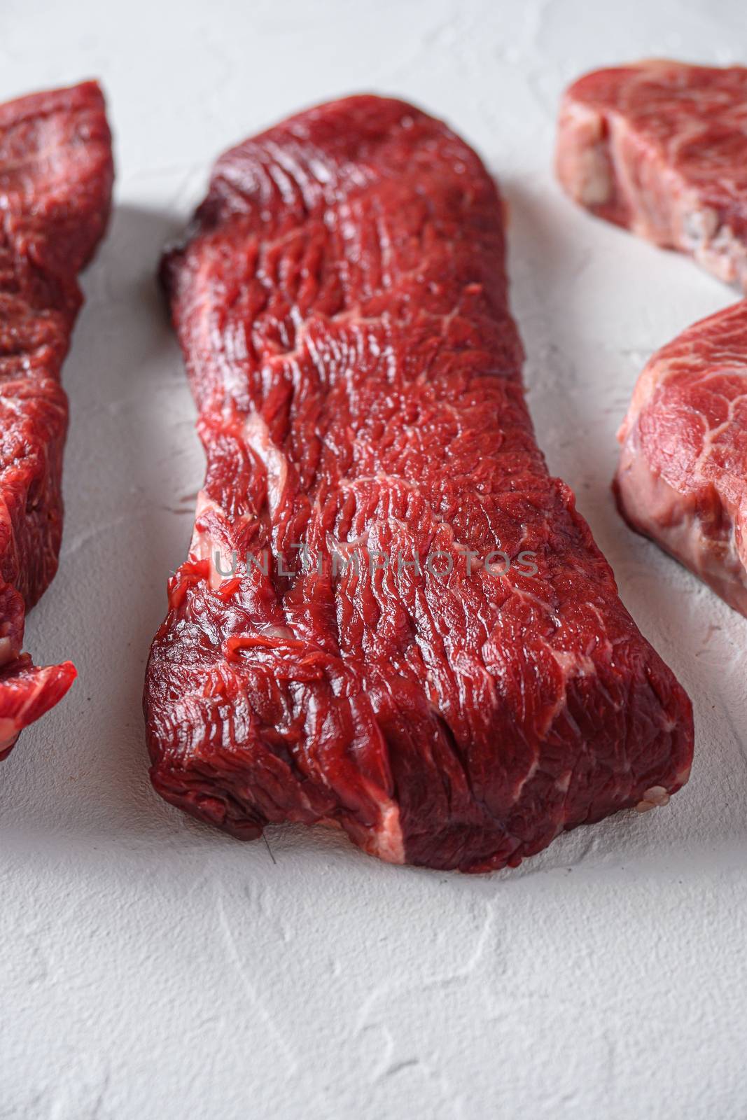 Raw tri-tip triangle roast or bottom sirloin steak cut organic meat cut side view close up over white concrete background vertical selective focus.