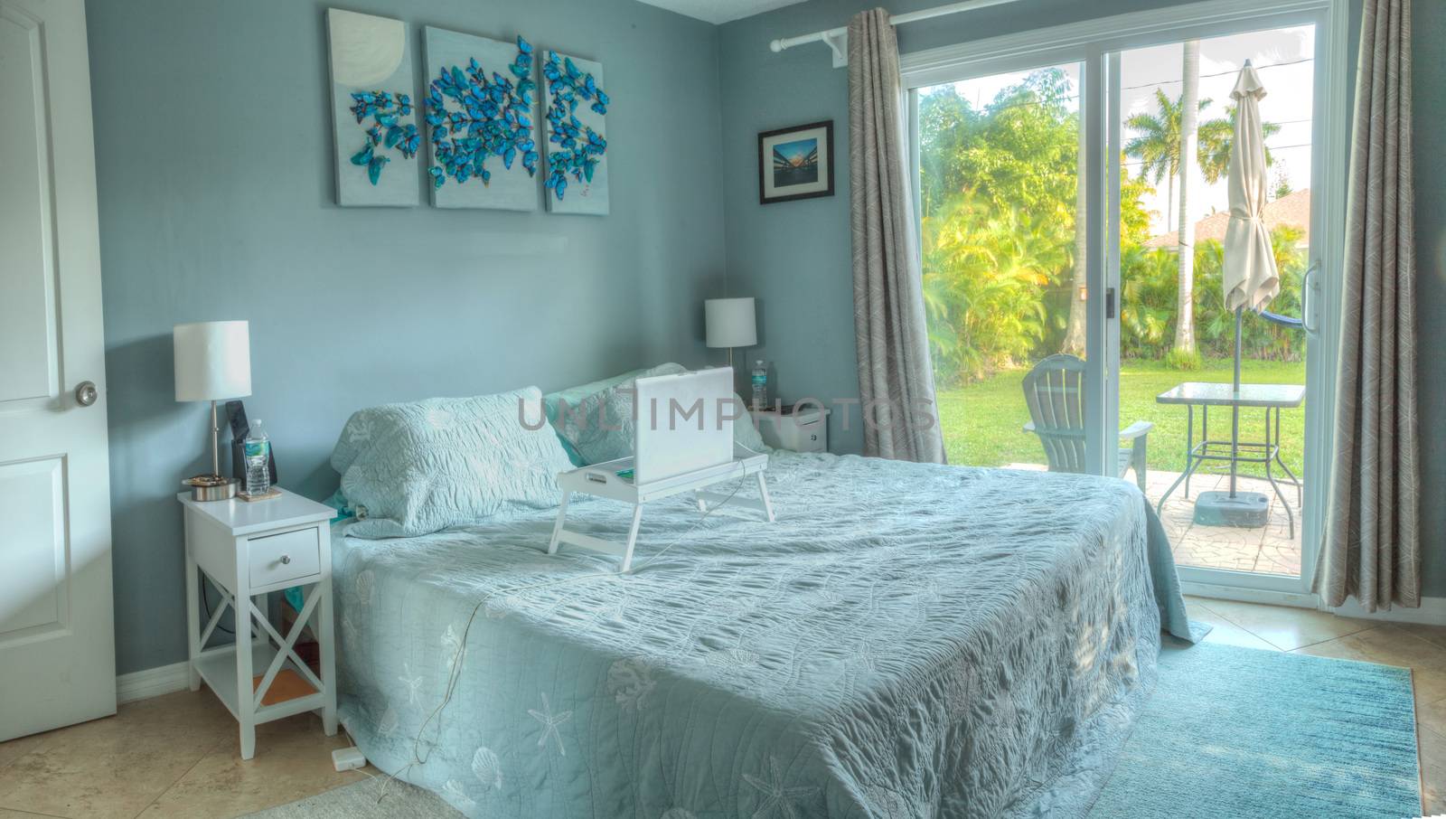 Garden view from a tranquil bedroom done in tropical blues with a Florida architectural design style.