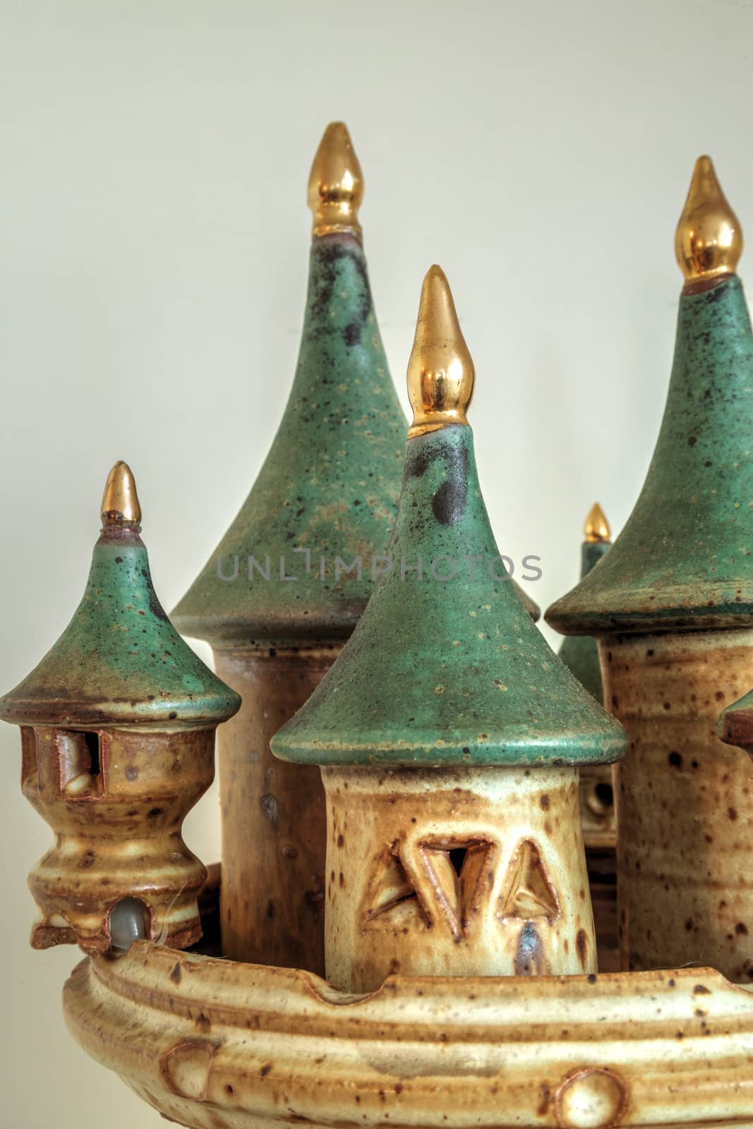 Pottery castle with turrets tipped in gold against a white background.