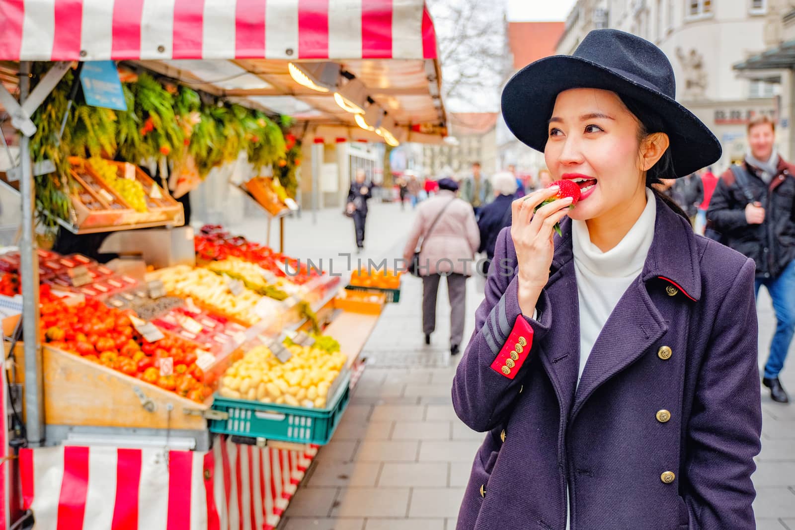 Beautiful Woman eating fresh strawberry on the street market in Germany