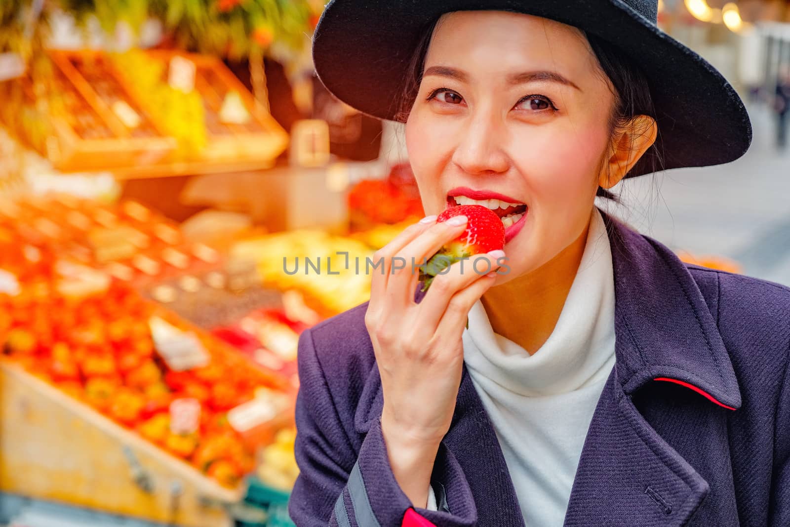 Beautiful Woman eating fresh strawberry on the street market in Germany