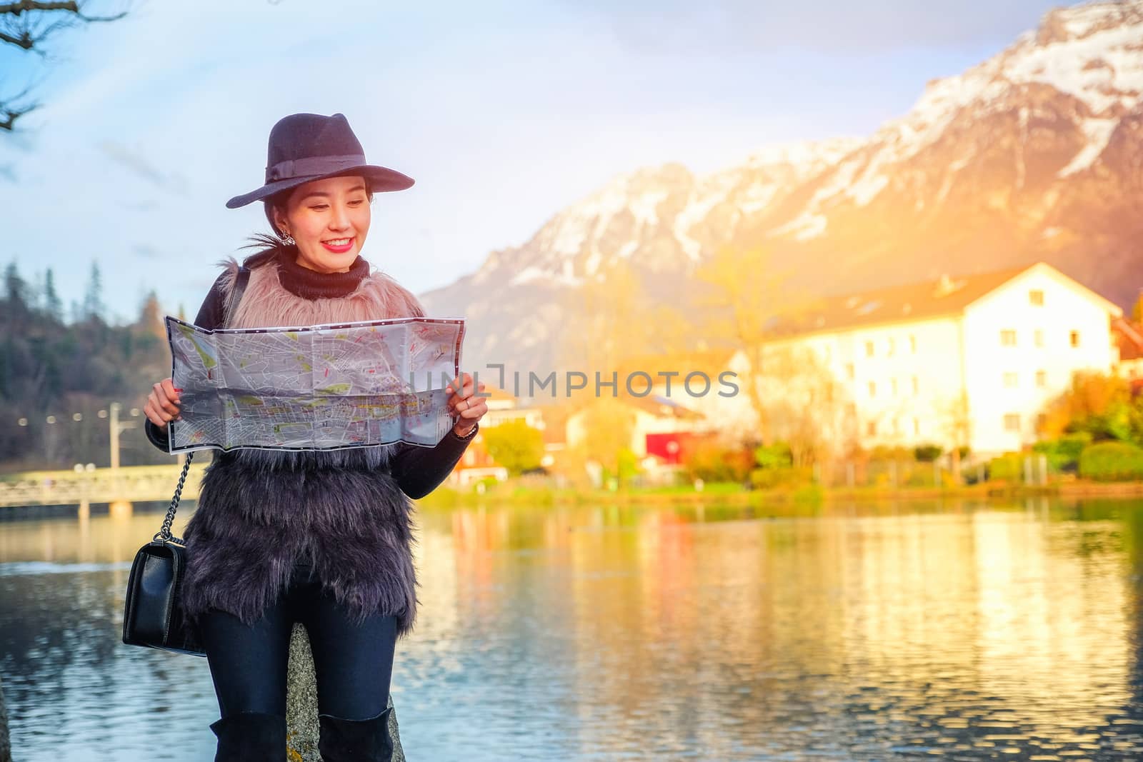 Young female tourist with map looking for a way to Beautiful view of Interlaken old town in Switzerland, Europe.