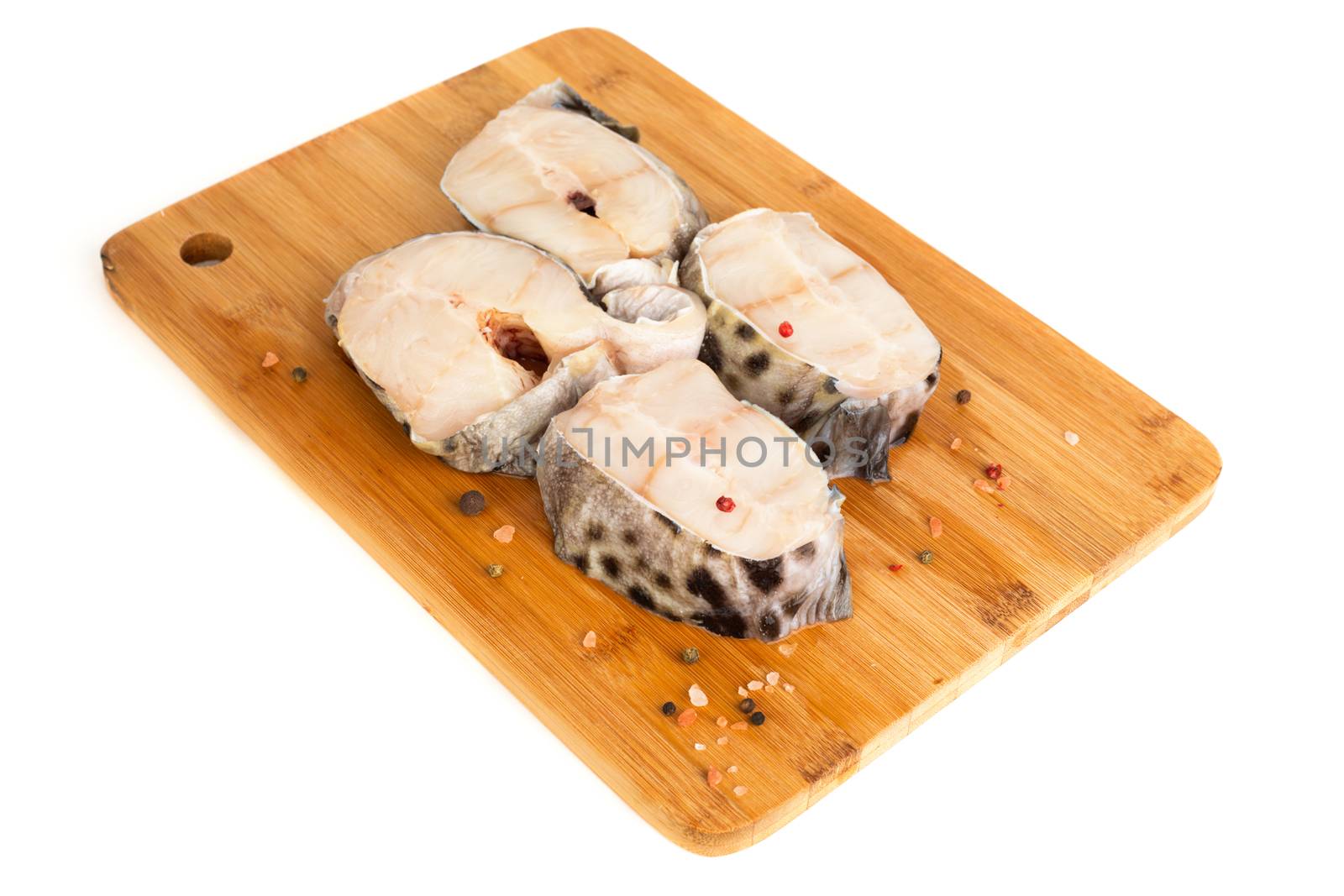 Raw catfish fish steaks on wooden cutting board studio isolated on white background