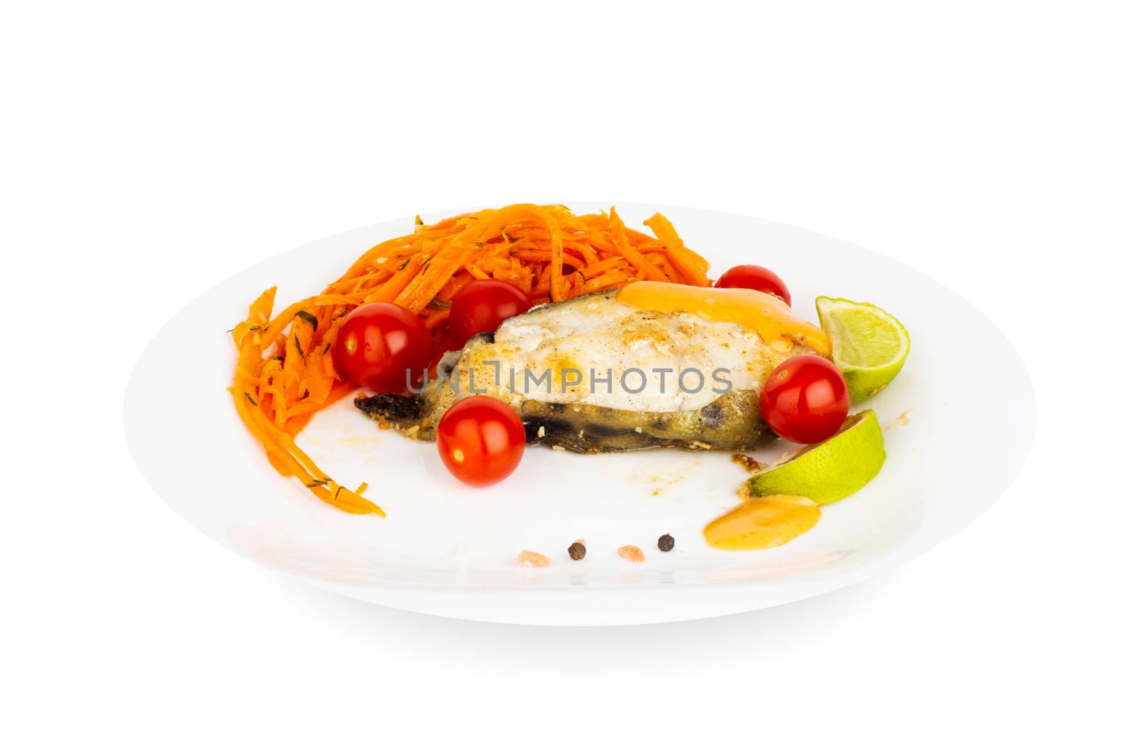 Fried cooked catfish steak with garnish of sauce and vegetables on white plate isolated on white background