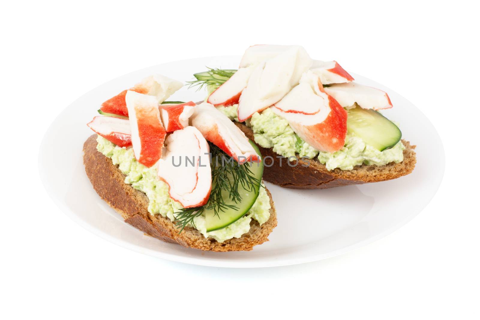 Crab sticks cut meat and vegetables avocado cucumbers sauce on rye bread sadswich on plate isolated on white background