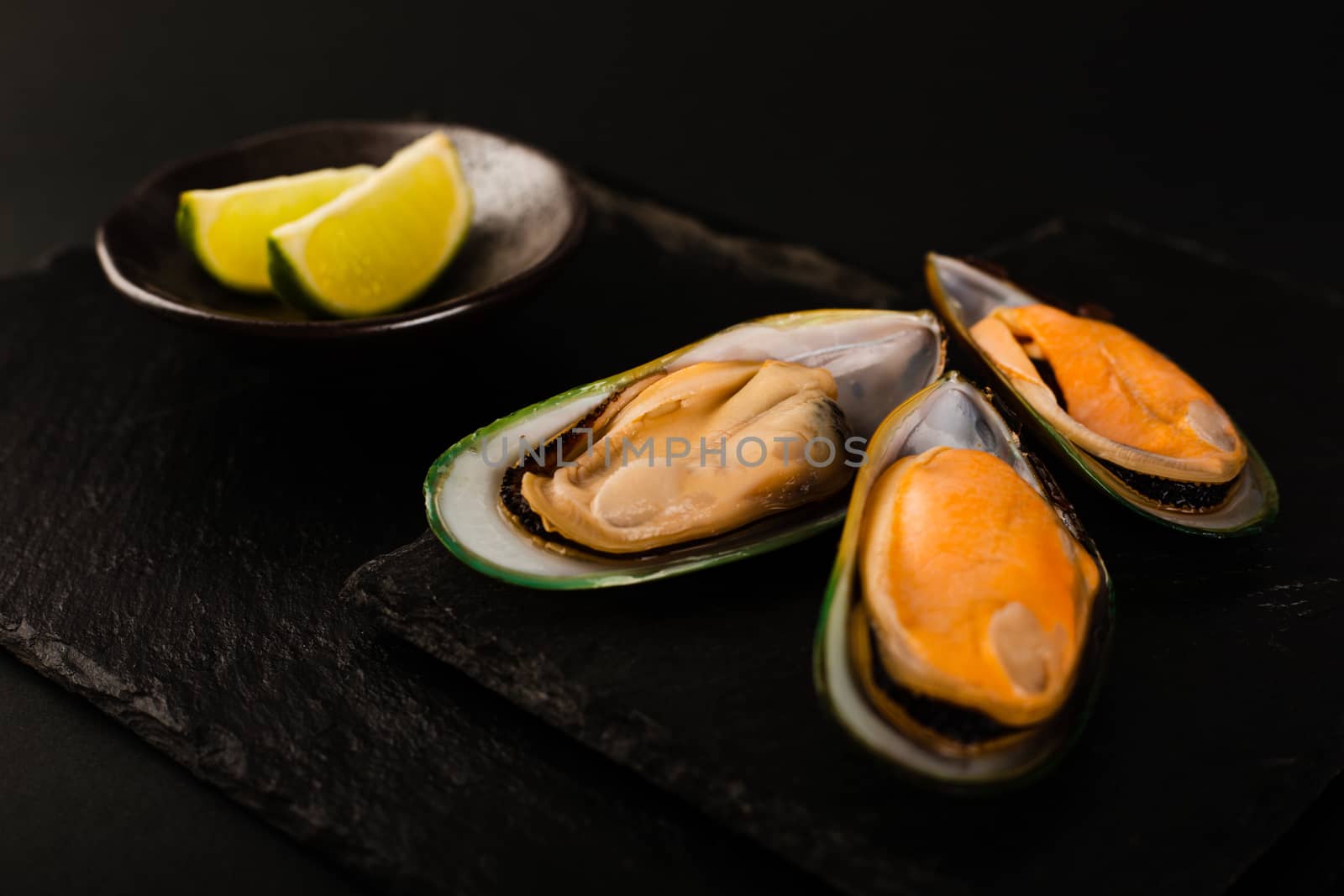 New Zealand greenshell mussels on black stone plate background and lime stylish luxury studio shot