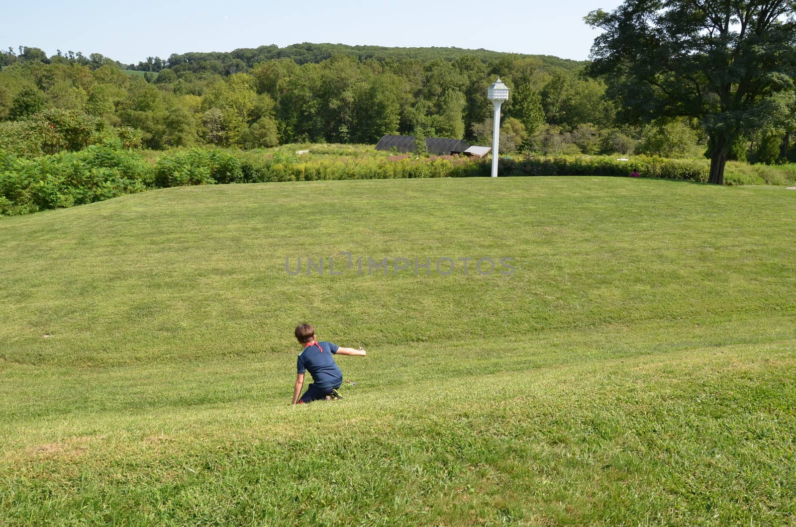 boy child rolling down a grass hill or lawn