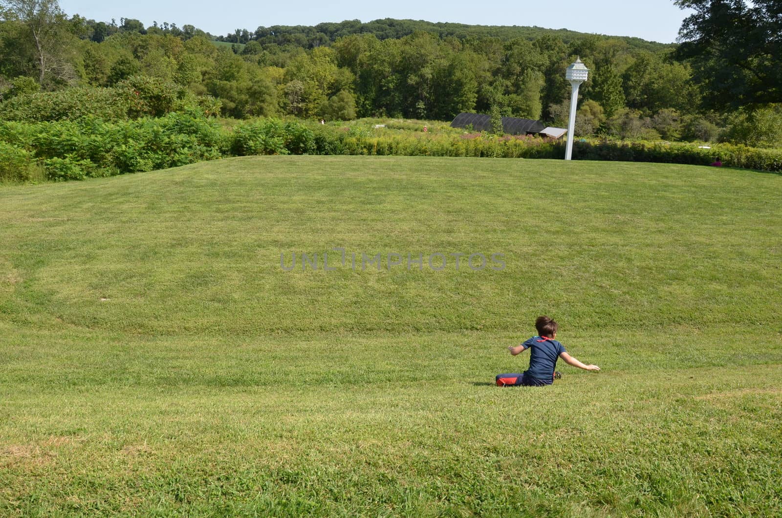 boy child rolling down a grass hill or lawn