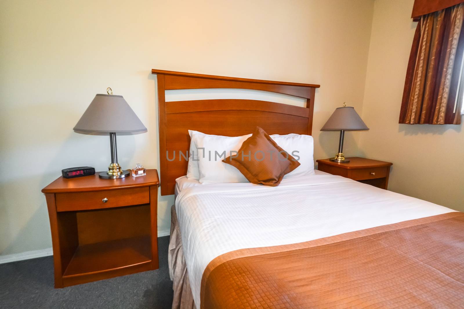 Interior of hotel bedroom with radio watch, perfume vail, and lamps on bedside tables