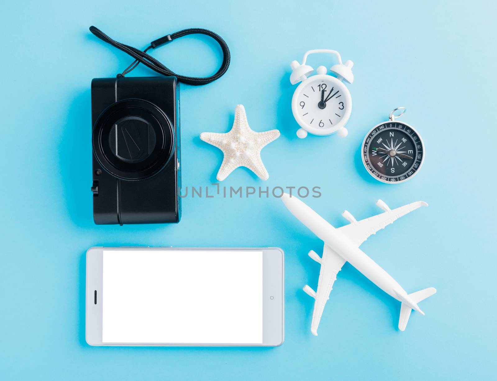 World Tourism Day, Top view of minimal model plane, airplane, starfish, alarm clock, compass and smartphone blank screen, studio shot isolated on a blue background, accessory flight holiday concept