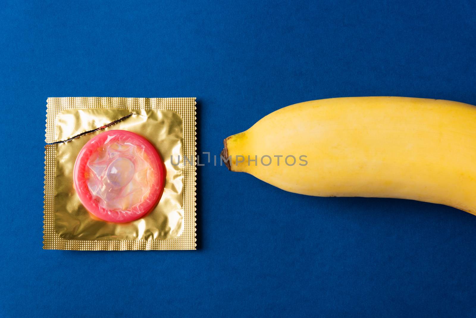 World sexual health or Aids day, Top view flat lay condom on wrapper pack and yellow banana, studio shot isolated on a pink background, Safe sex and reproductive health concept