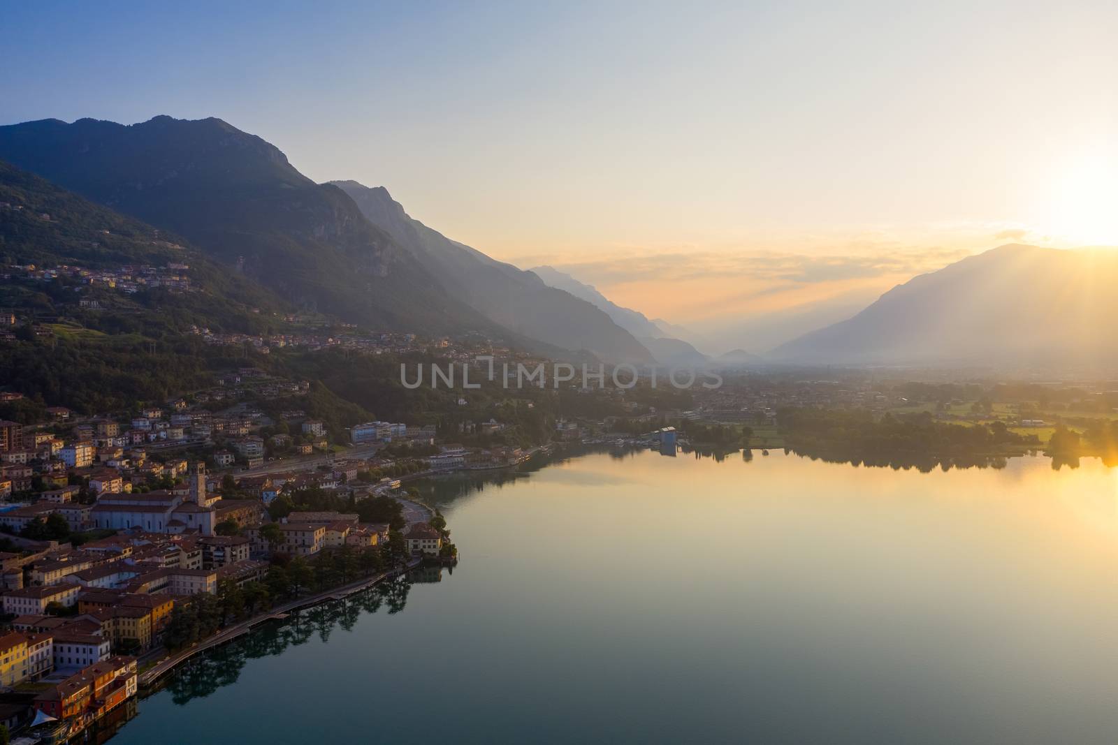 Drone view of Lake Iseo at sunrise, on the left the city of lovere which runs along the lake,Bergamo Italy.