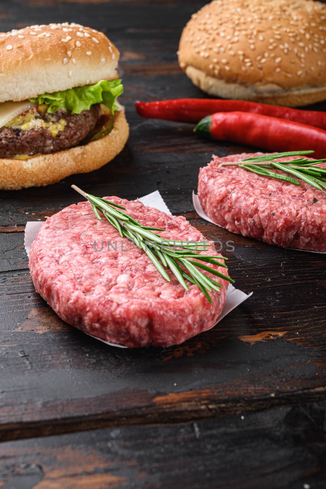 Raw ground beef meat burger steak cutlets on dark wooden background.