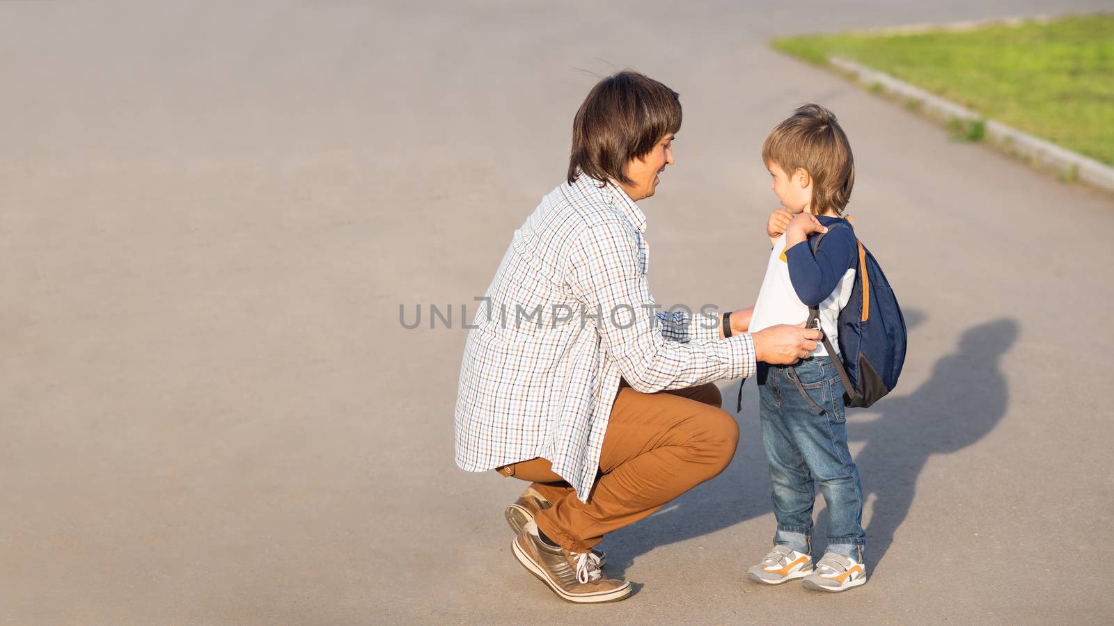 Father takes his son to school. Back to school after summer holidays. Dad and kid on street. Family time, moral support. Banner with copy space.