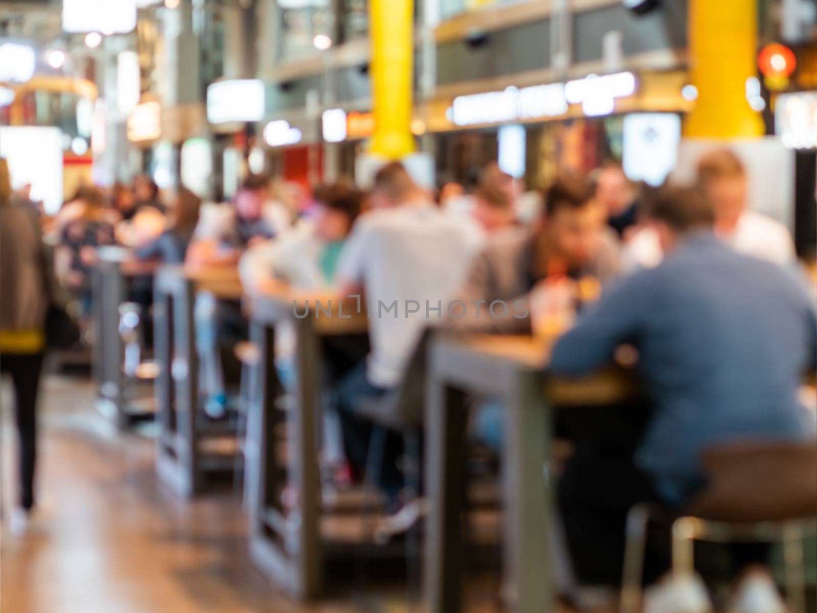 Food court at shopping mall. People are eating without protective masks and social distance. New normal situation after end of coronavirus COVID-19 pandemia. Blurred background.