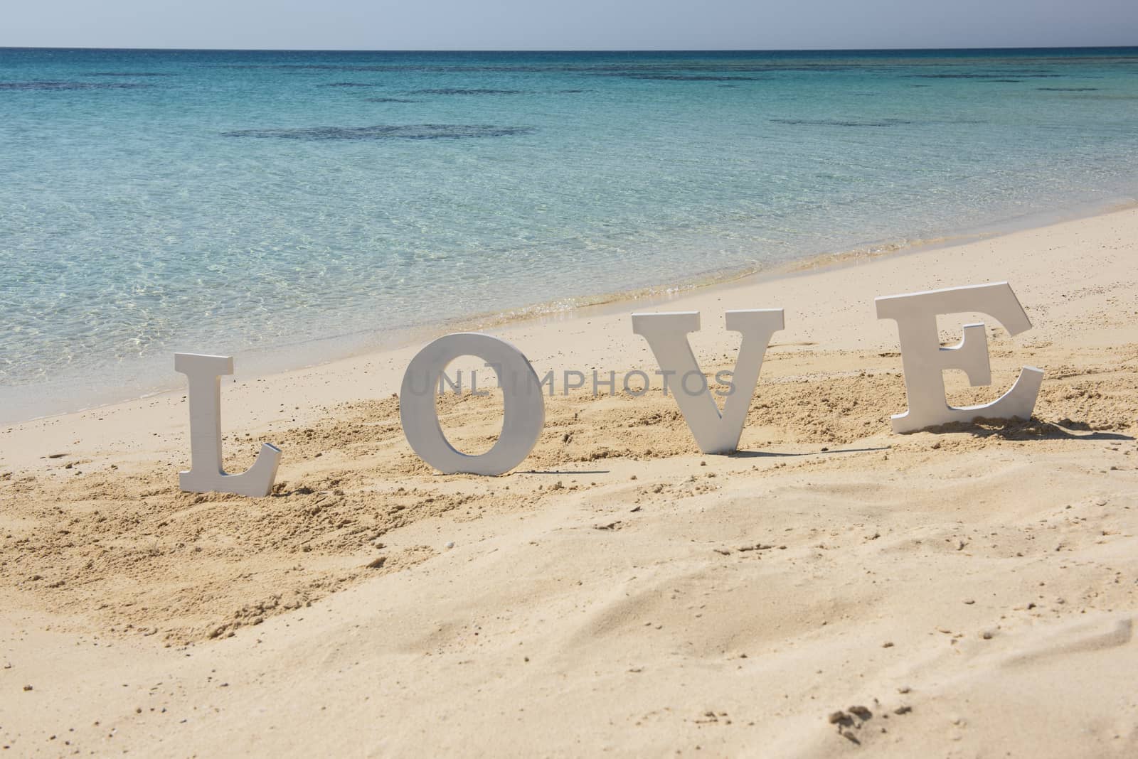 Closeup of romantic love sign on tropical island sandy beach paradise with ocean in background