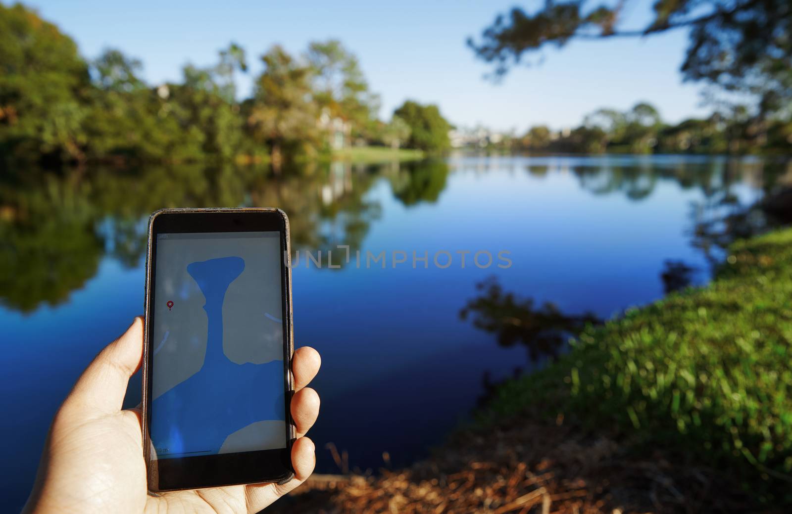 Man using mobile map app next to the lake by Novic