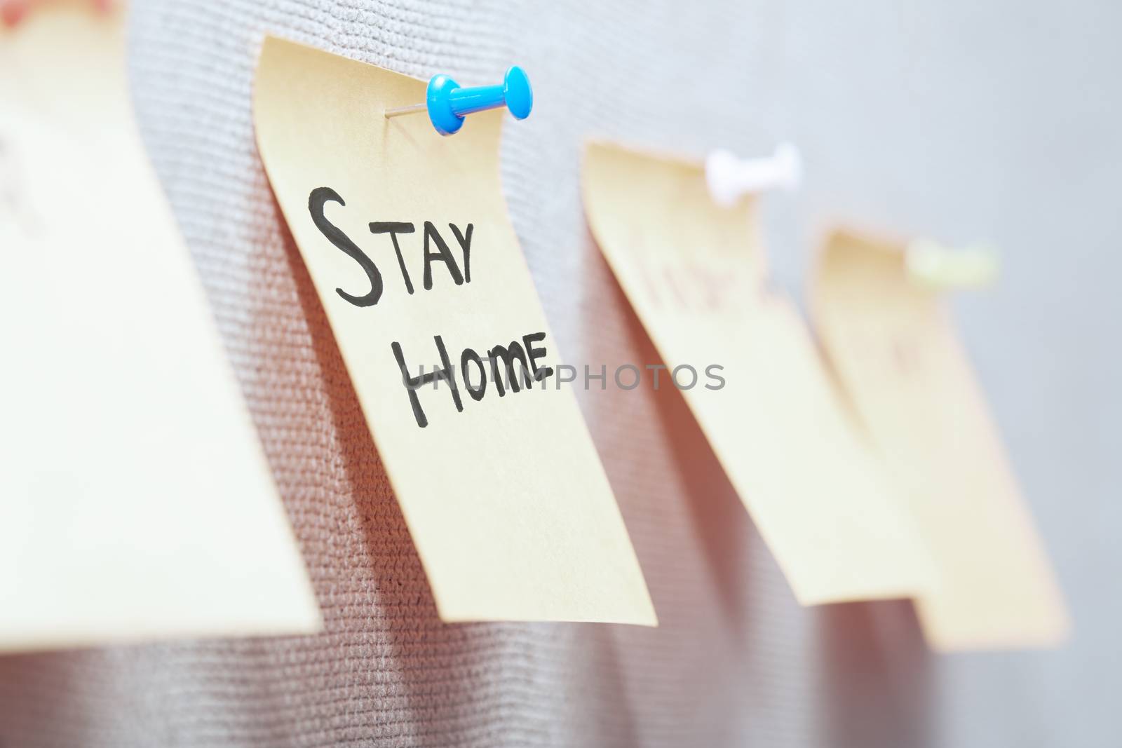 Adhesive note with Stay Home text on a bulletin board by Novic